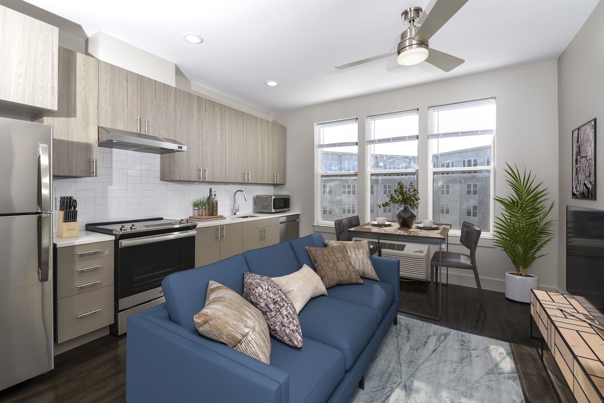 Modern apartment interior with a blue sofa, kitchen, and dining area.