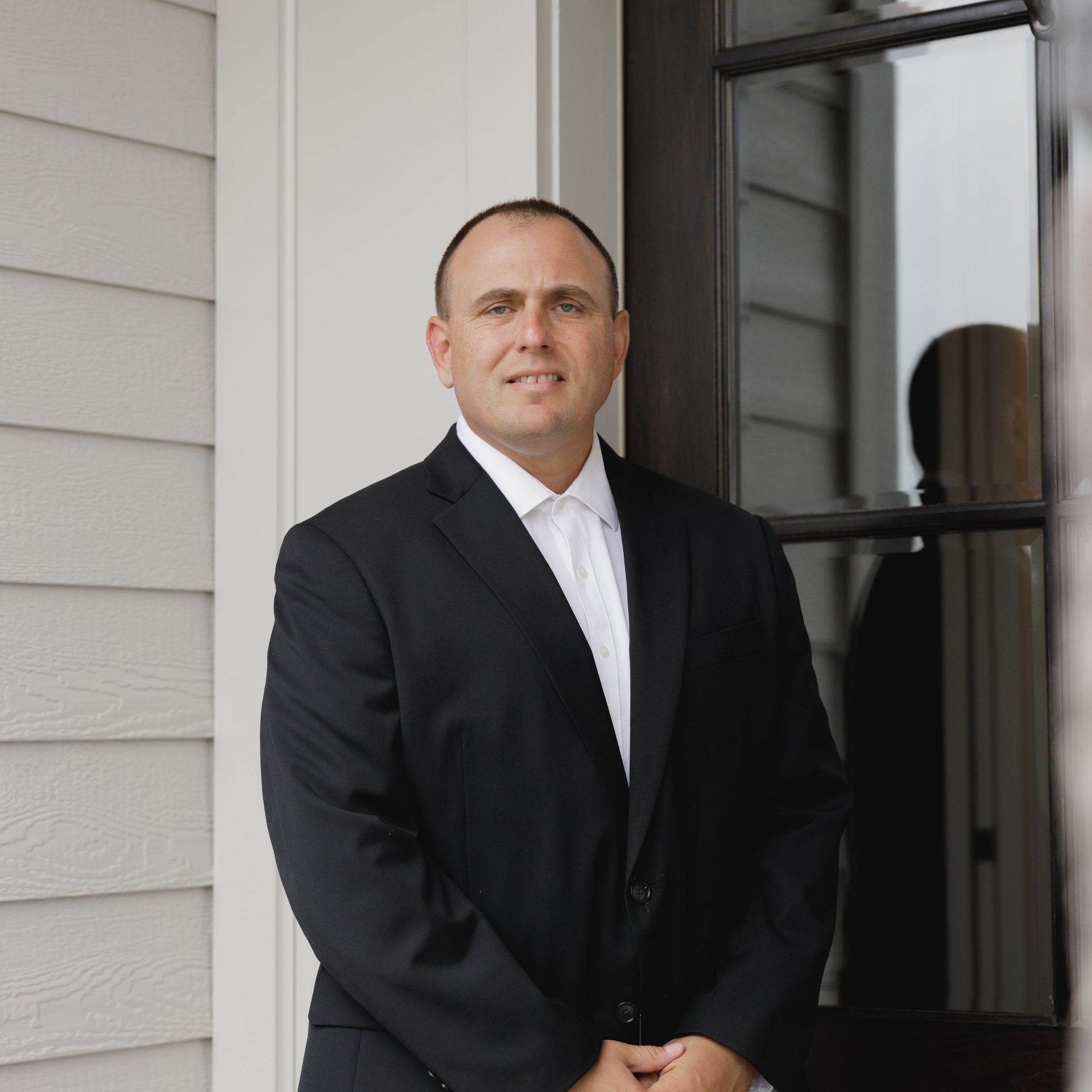 A man in a suit and tie is standing in front of a door.