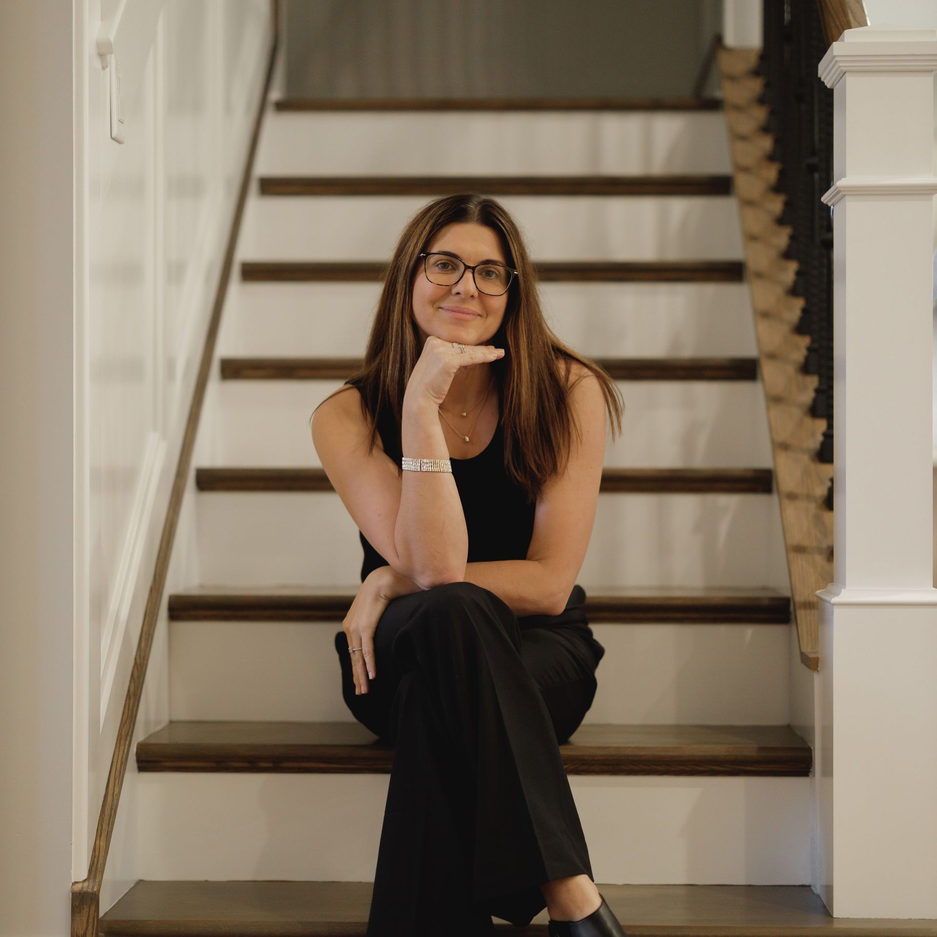 A woman is standing next to a white couch in a living room.
