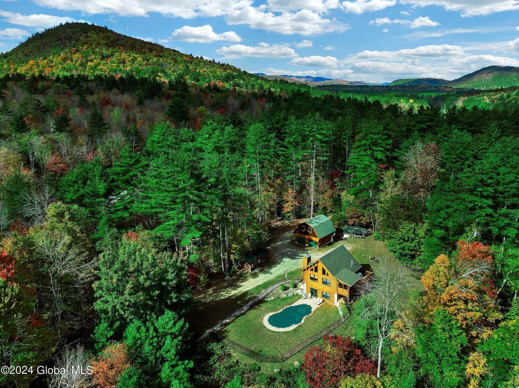 An aerial view of a house in the middle of a forest surrounded by trees.