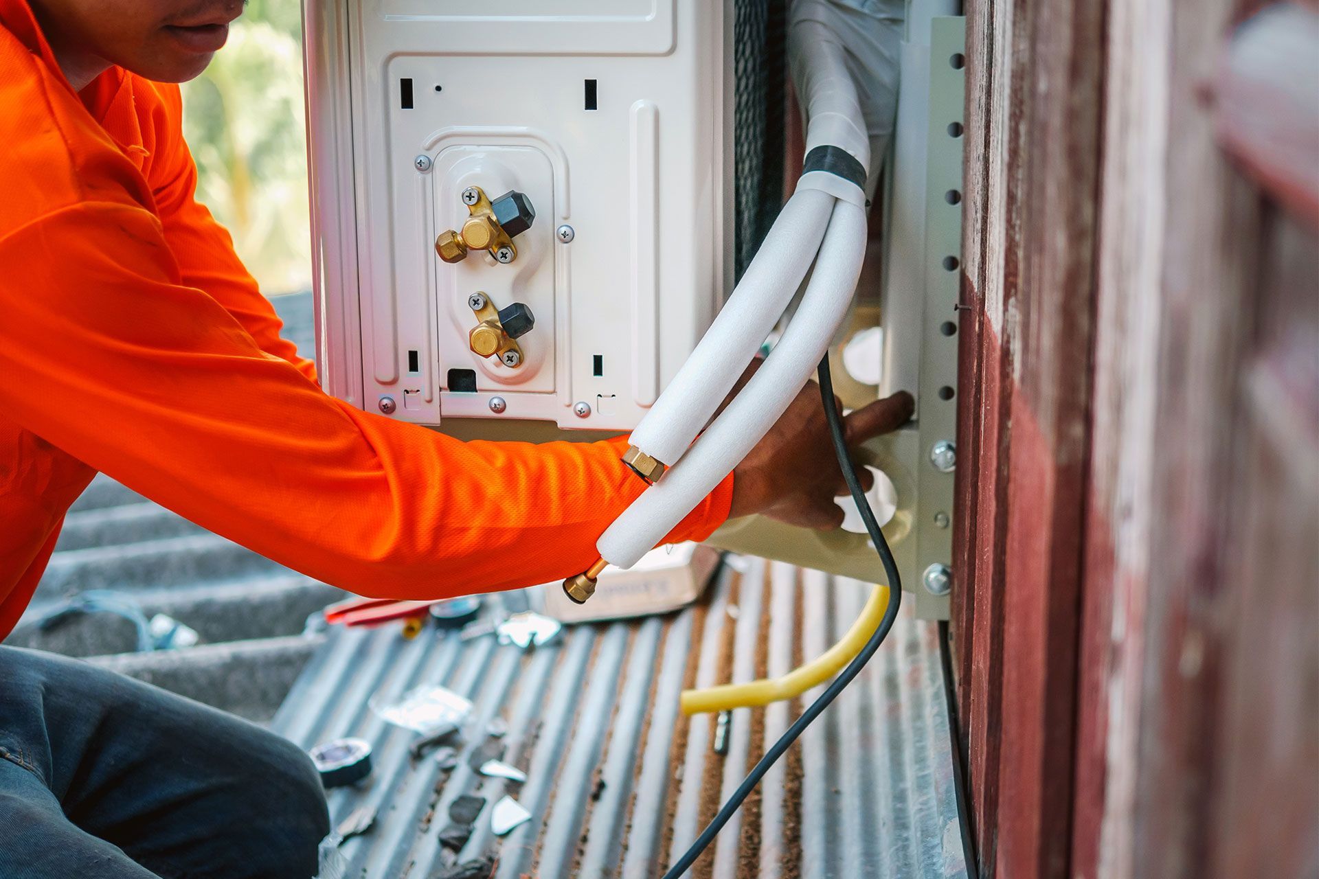 A man is installing an air conditioner on the side of a building.