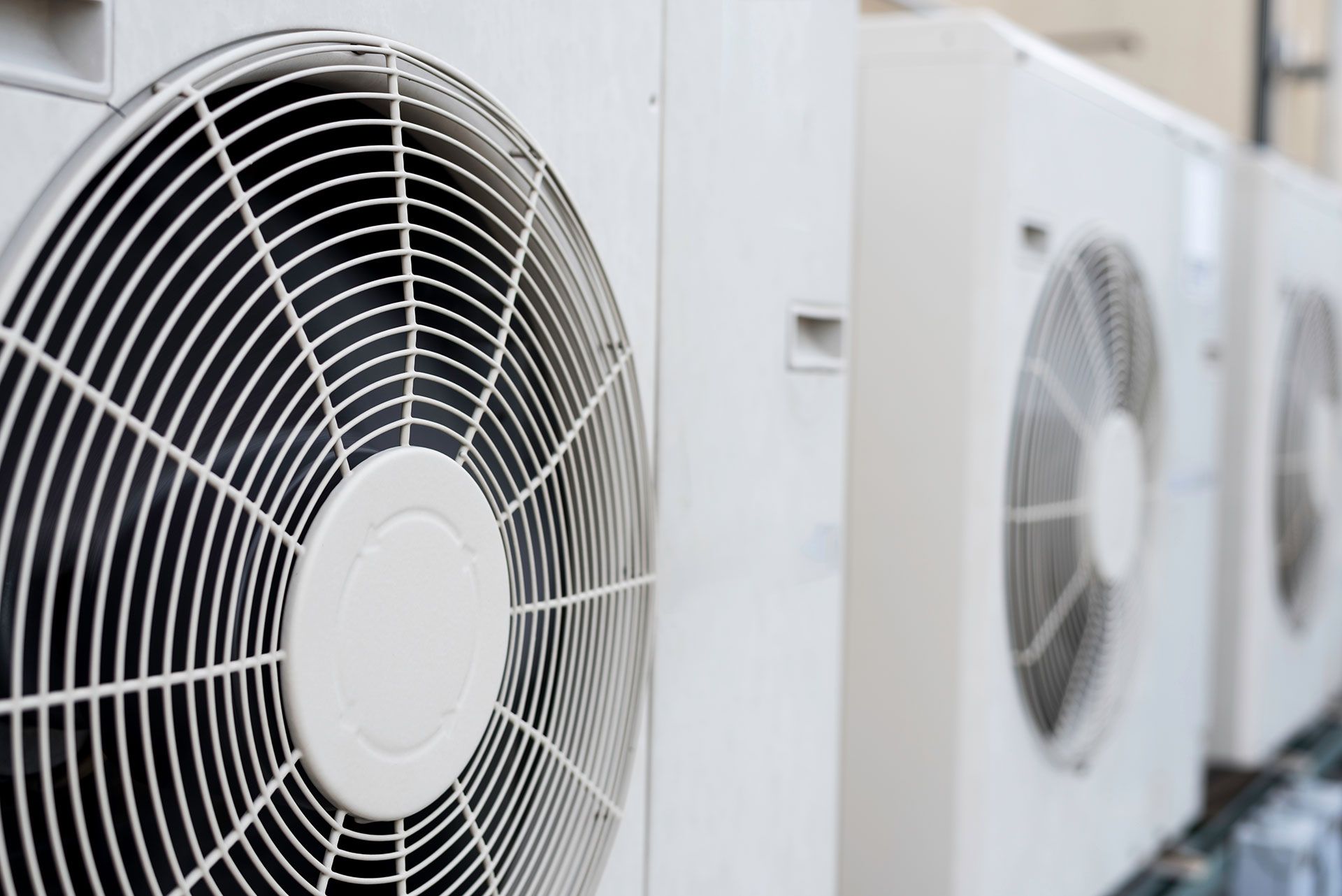 A row of air conditioners are sitting next to each other on the side of a building.