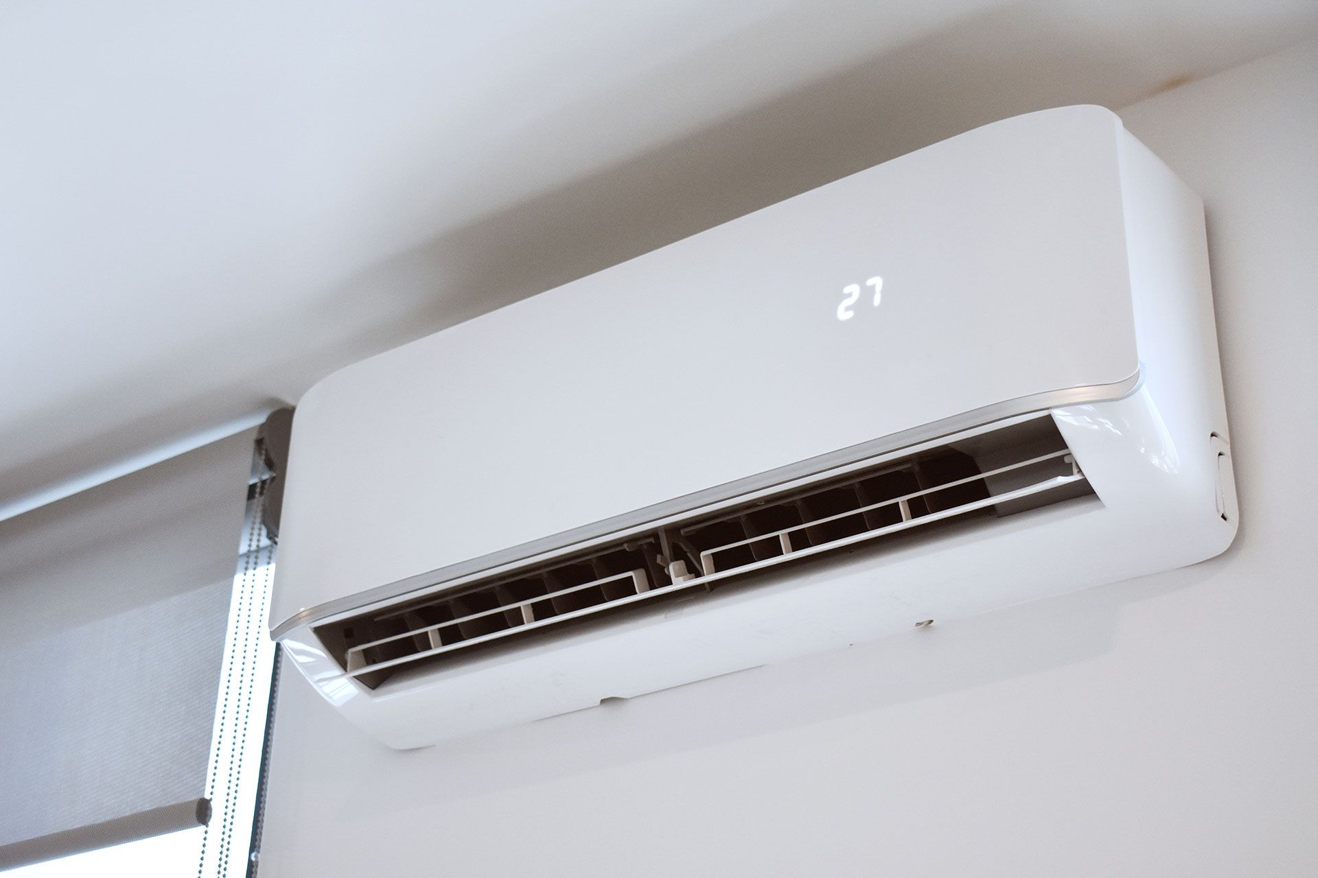 A white air conditioner is hanging from the ceiling in a room.