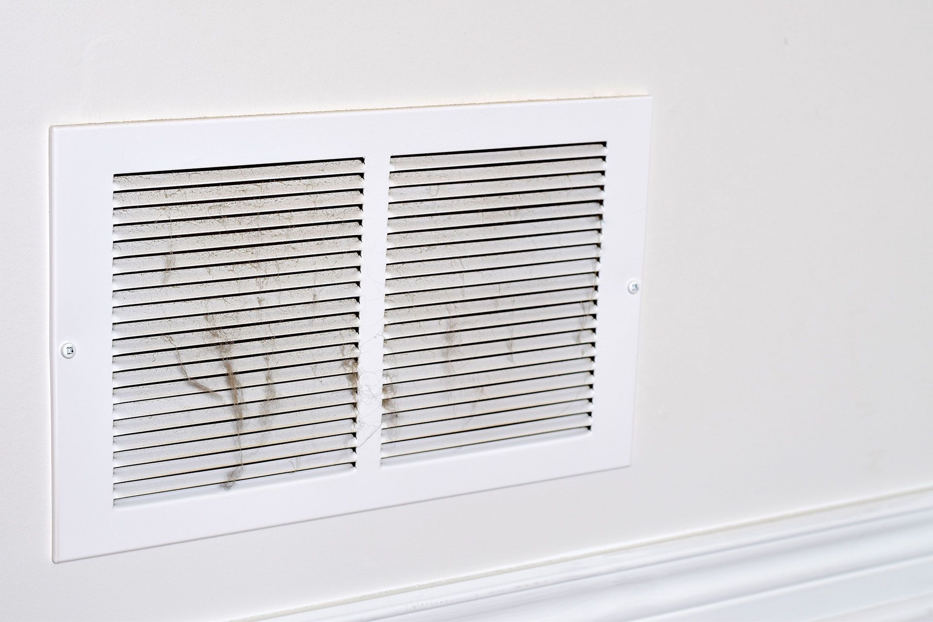 A close up of a white air vent on a wall.