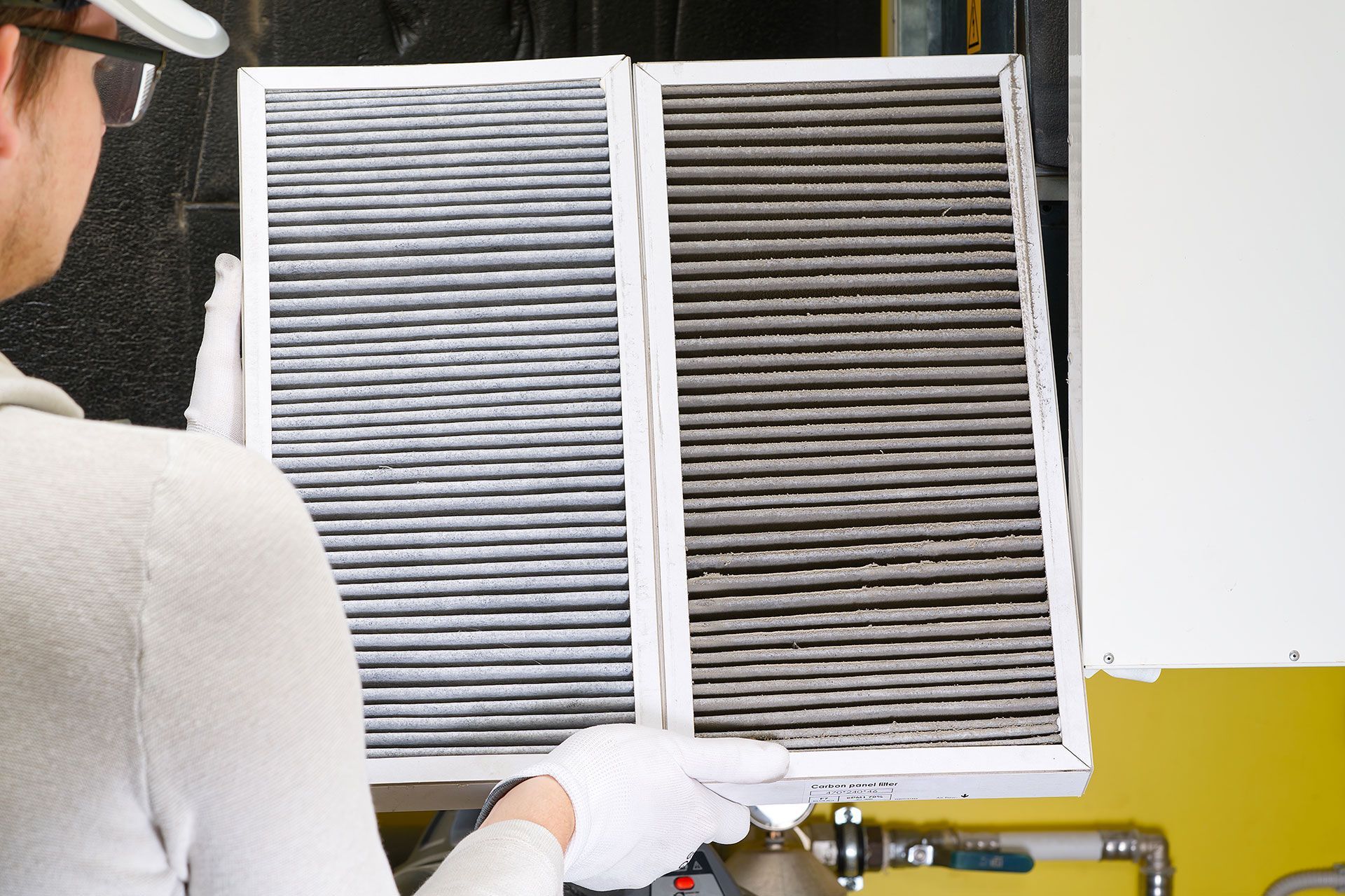 A man is holding two dirty air filters in his hands.