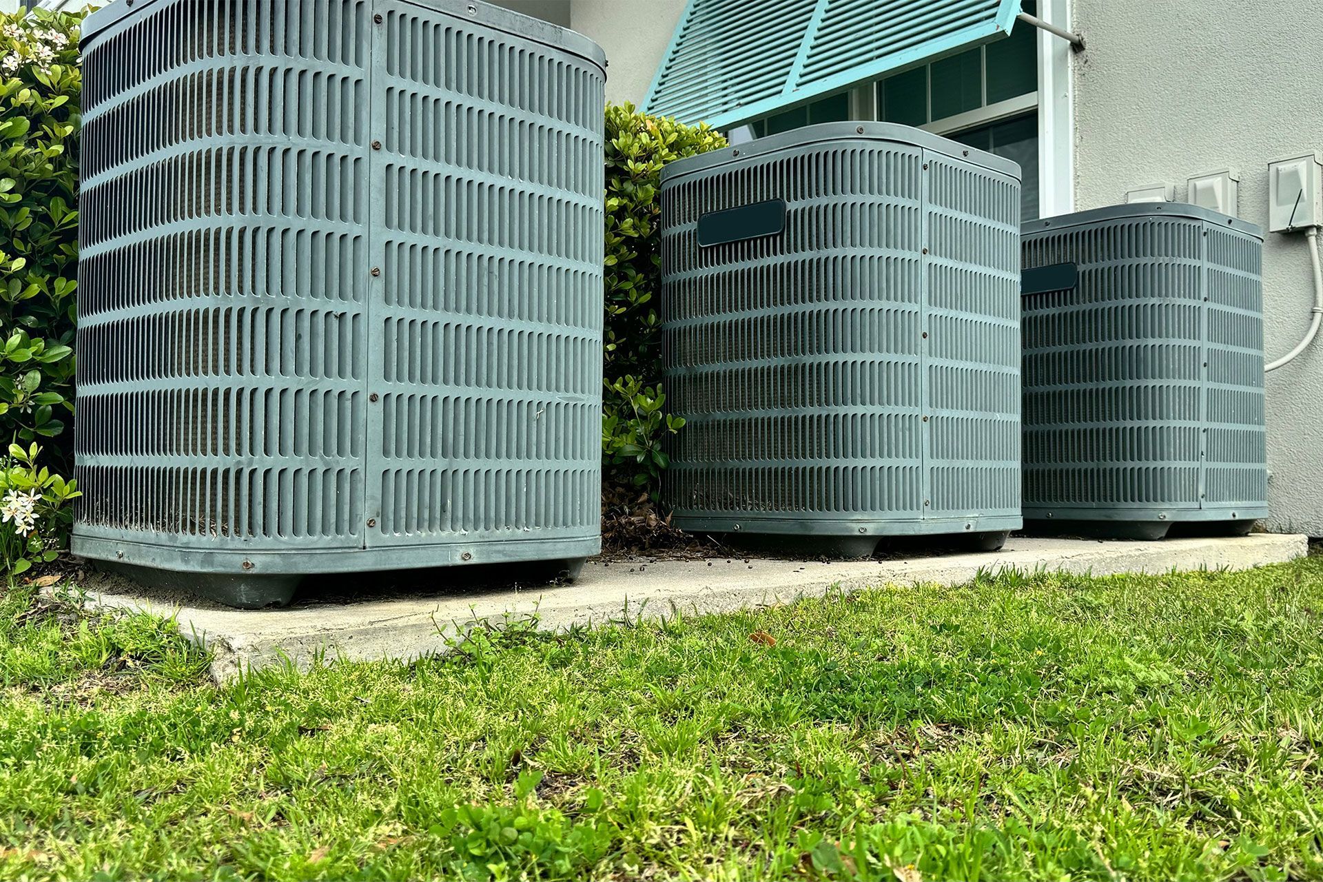 Three air conditioners are sitting on the side of a building.