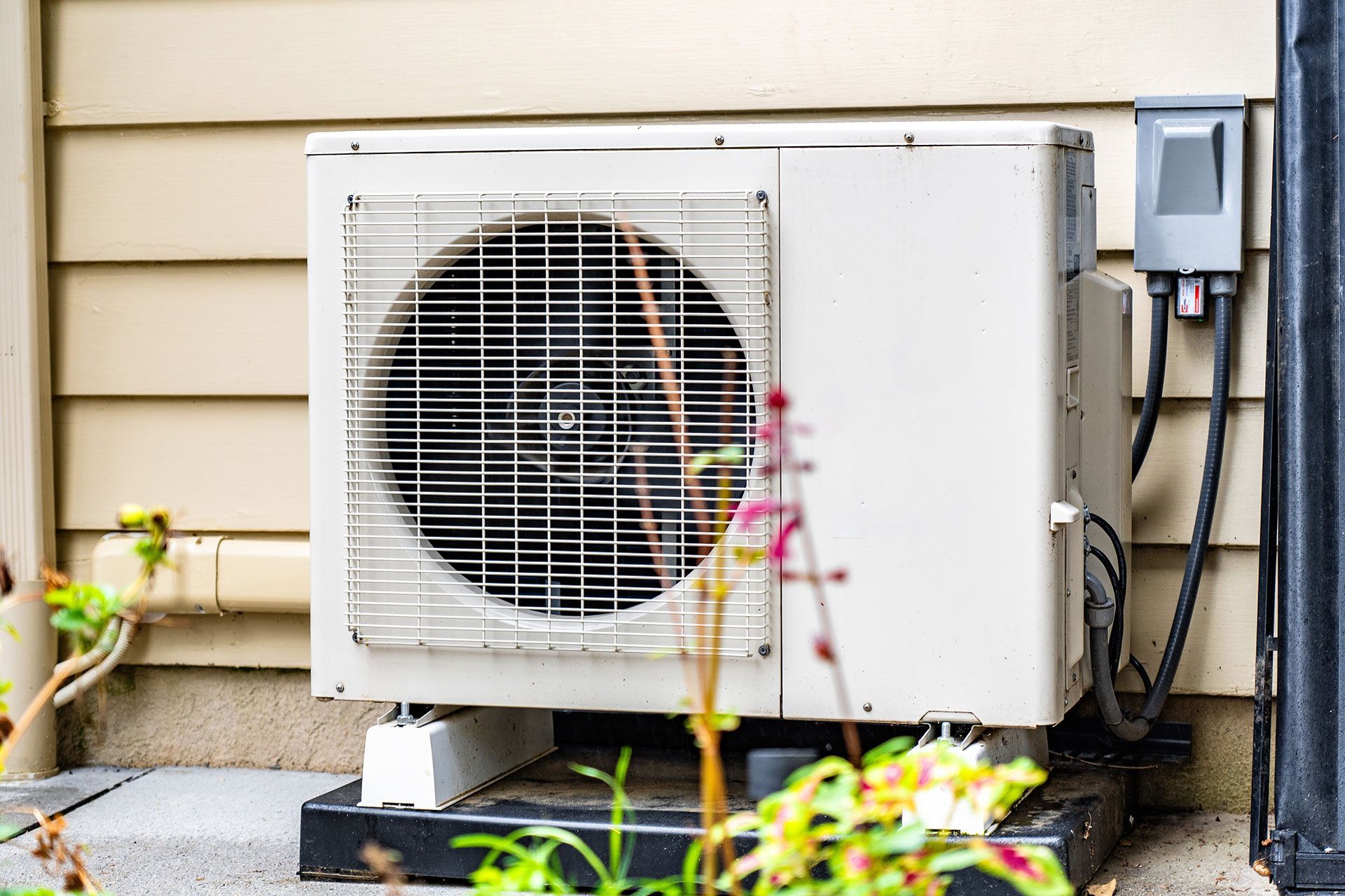 A white air conditioner is sitting on the side of a house.