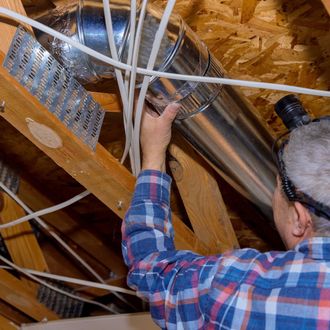 A man in a plaid shirt is working on a metal pipe