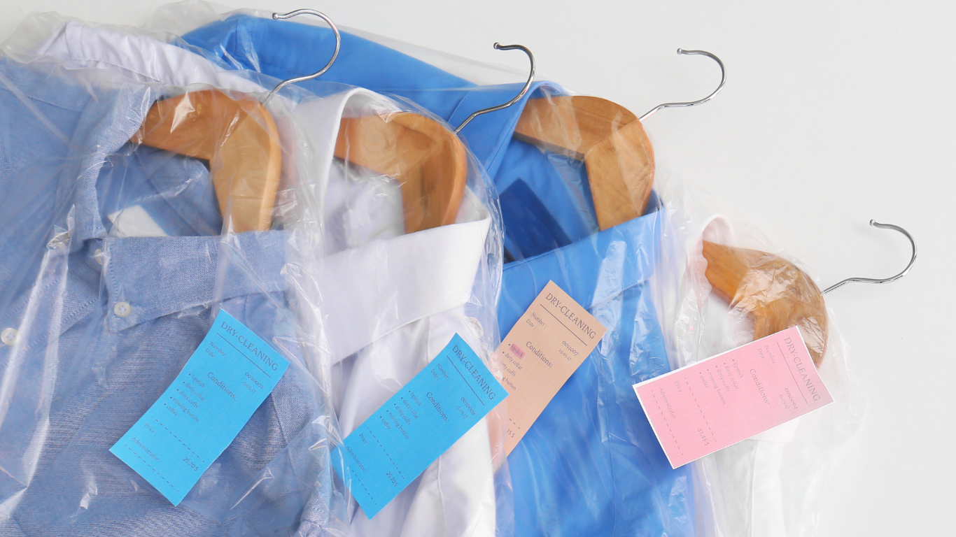 A person is holding a stack of white towels in their hands.