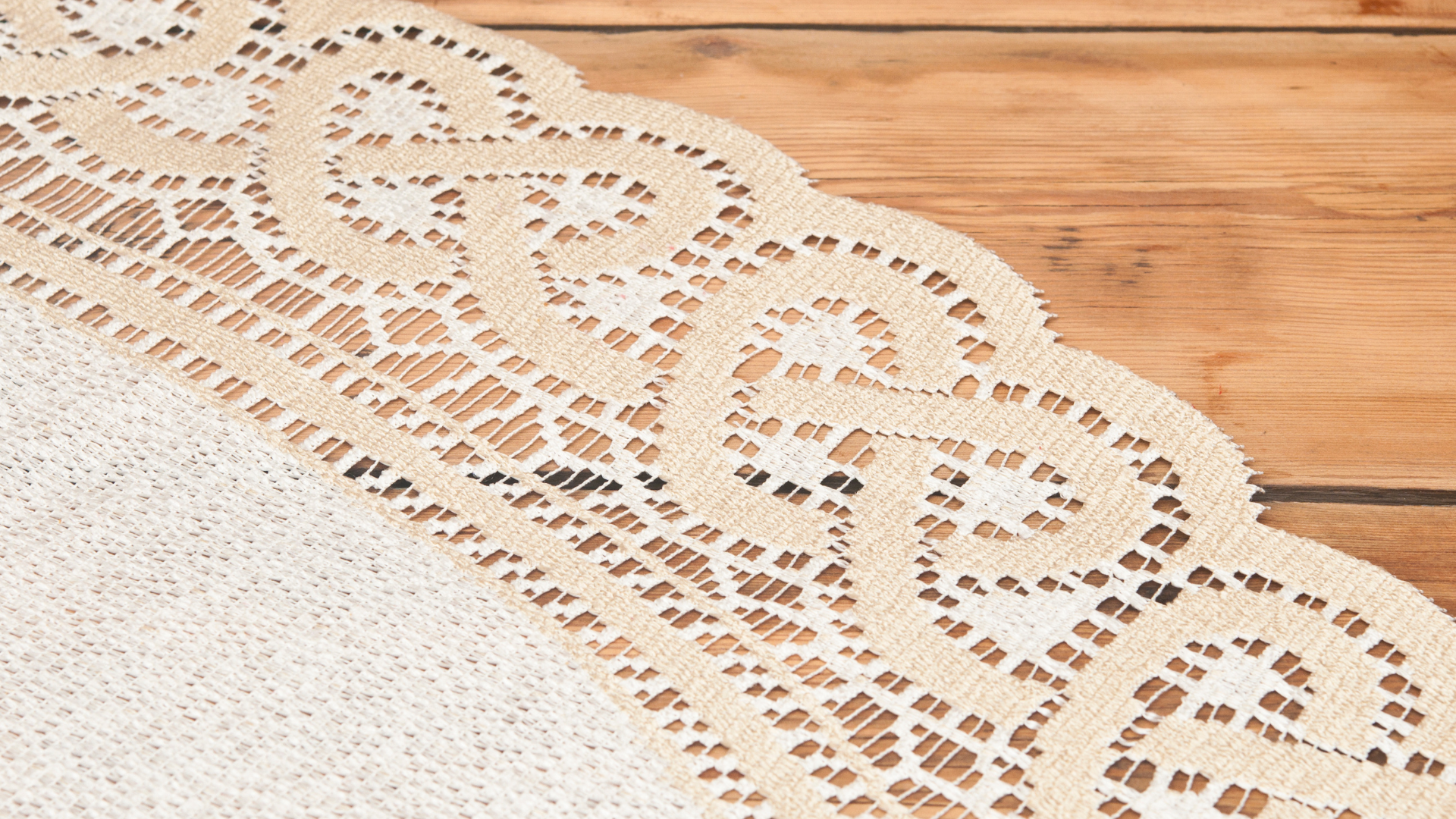 A white lace table runner is sitting on a wooden table.