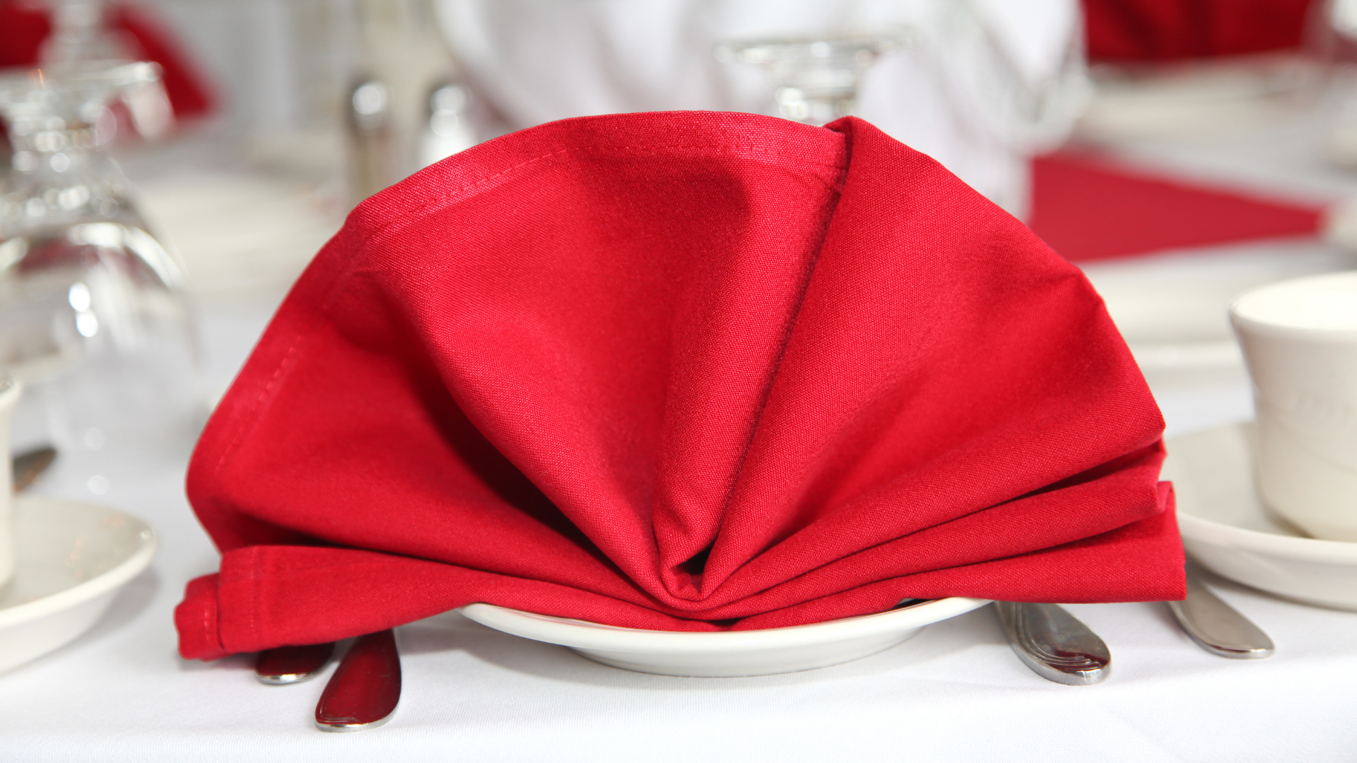 A red napkin is folded into a fan on a white plate