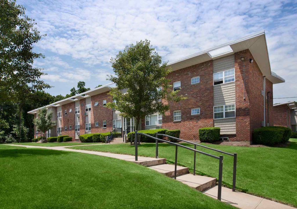 Concrete sidewalk leading away from apartment building. Steps on sidewalk with handrails
