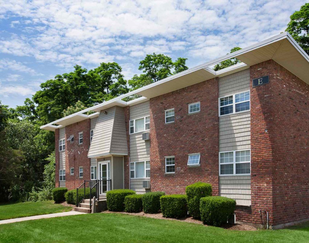 Two story brick apartment building with trees behind it