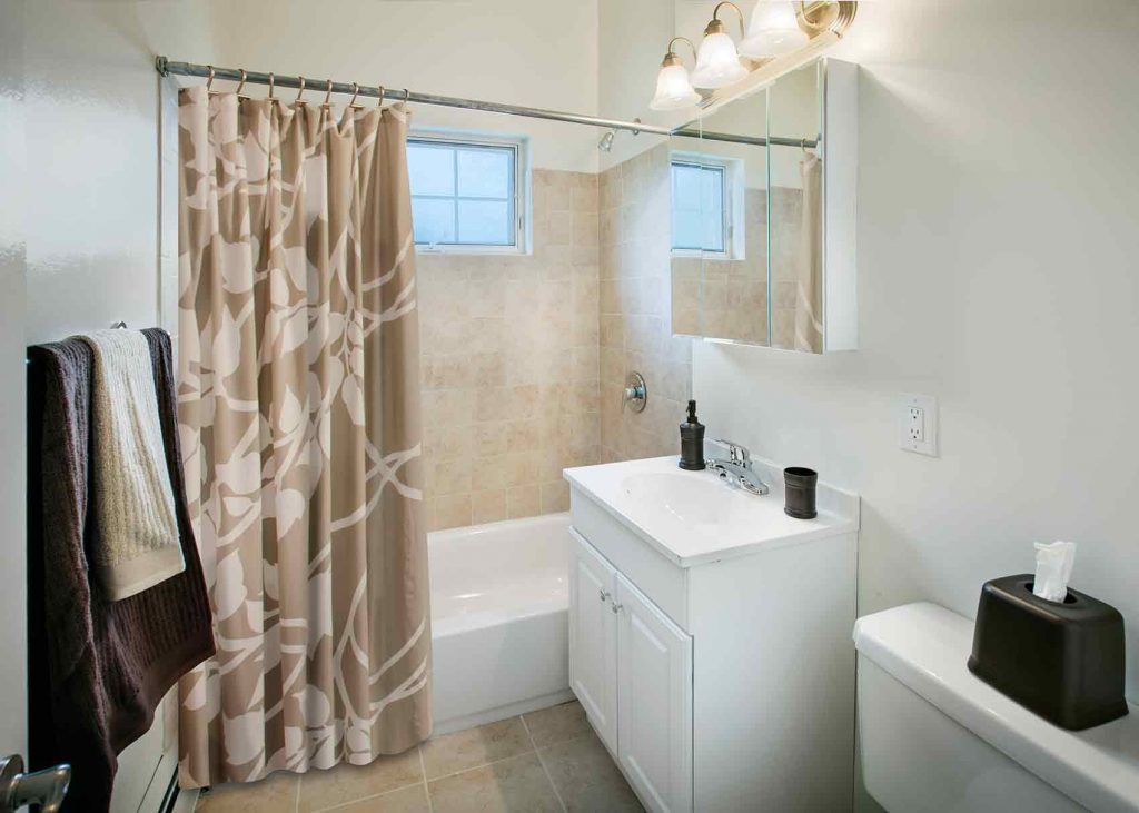 Bathroom with sink, toilet, and bathtub with shower tiling on wall around shower