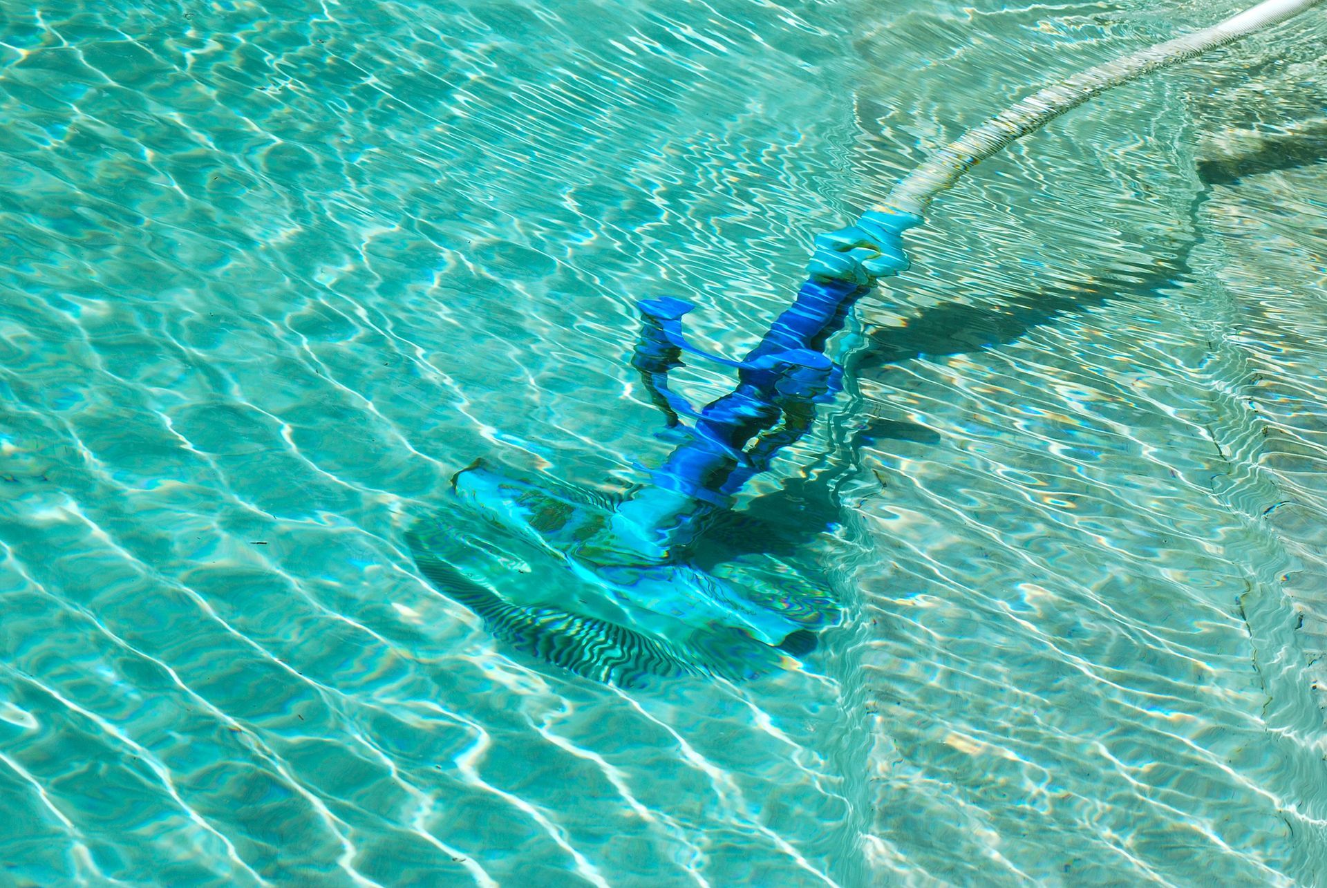 Aspirapolvere blu per piscina che pulisce una piscina turchese.