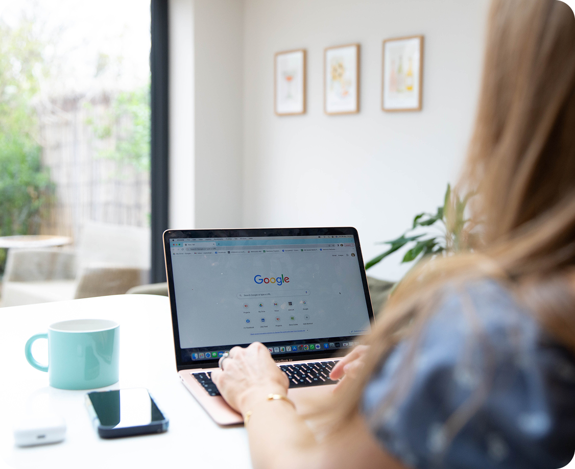 A woman is sitting at a table using a laptop computer.