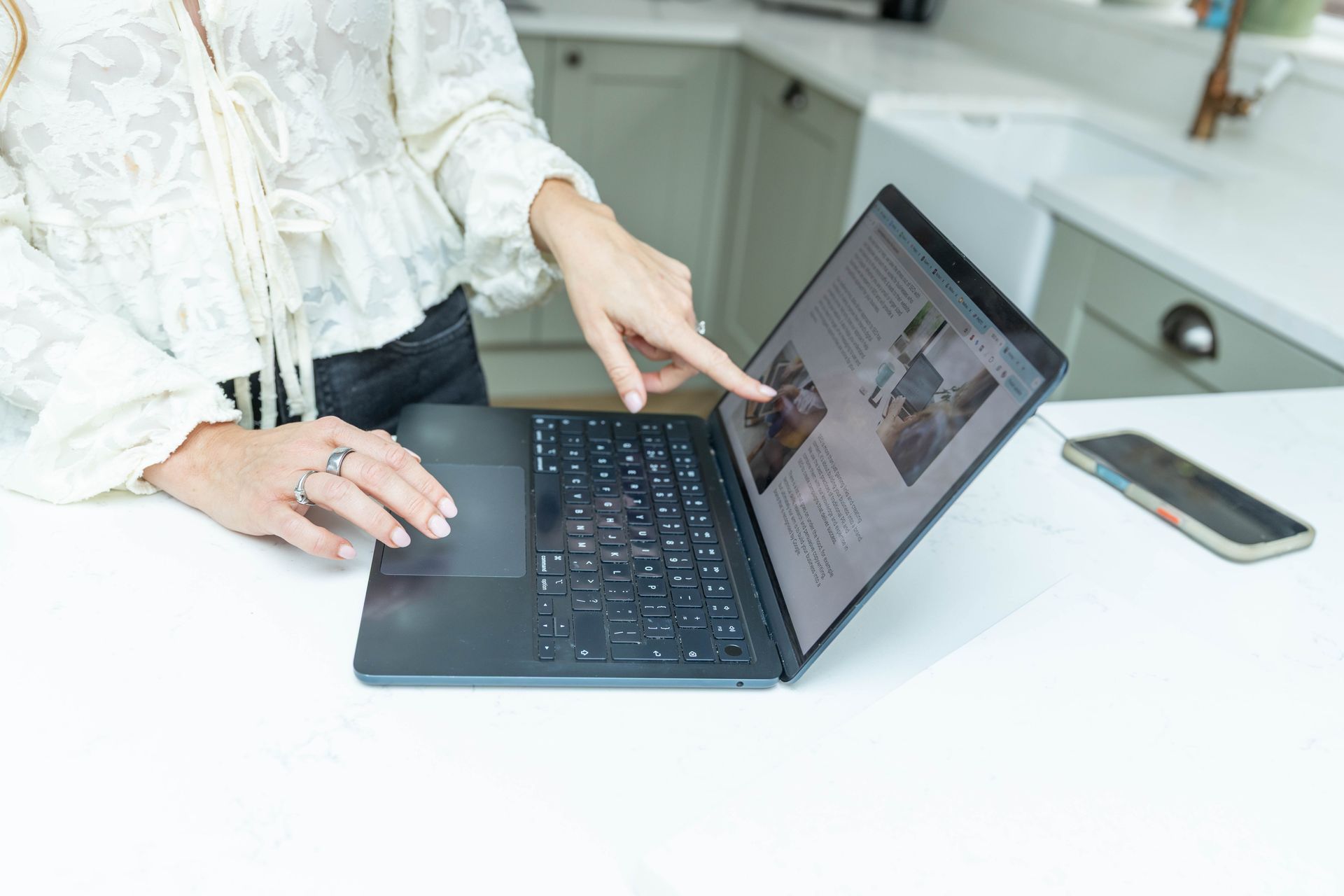 A person is holding a tablet next to a laptop computer.