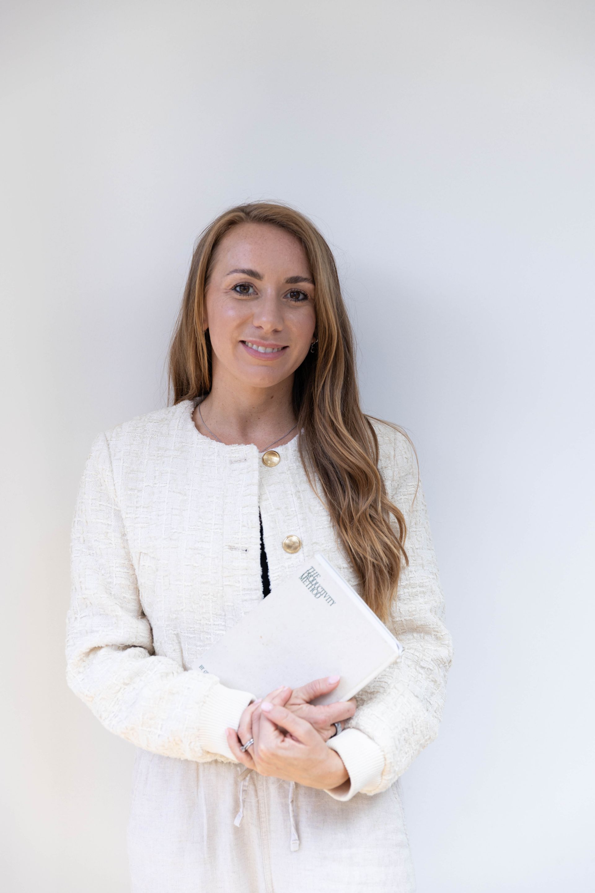 Two women smiling while looking at a laptop indoors. One holds a mug. Sunlight streams in from a window.