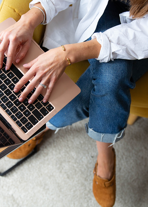 A woman is sitting in a chair using a laptop computer