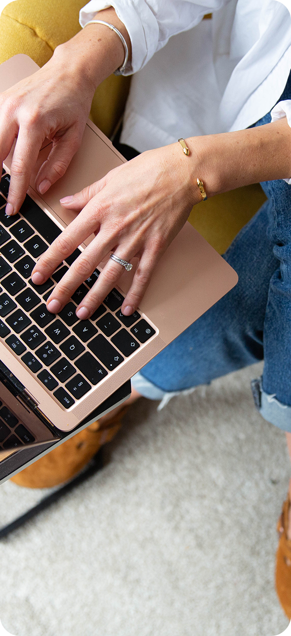 A woman is sitting on a couch using a laptop computer.