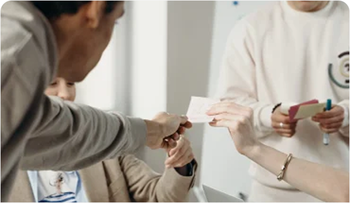 A man is handing a business card to another man.