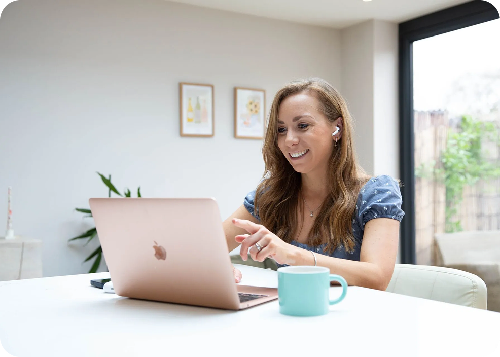 A woman is sitting at a table using a laptop computer.