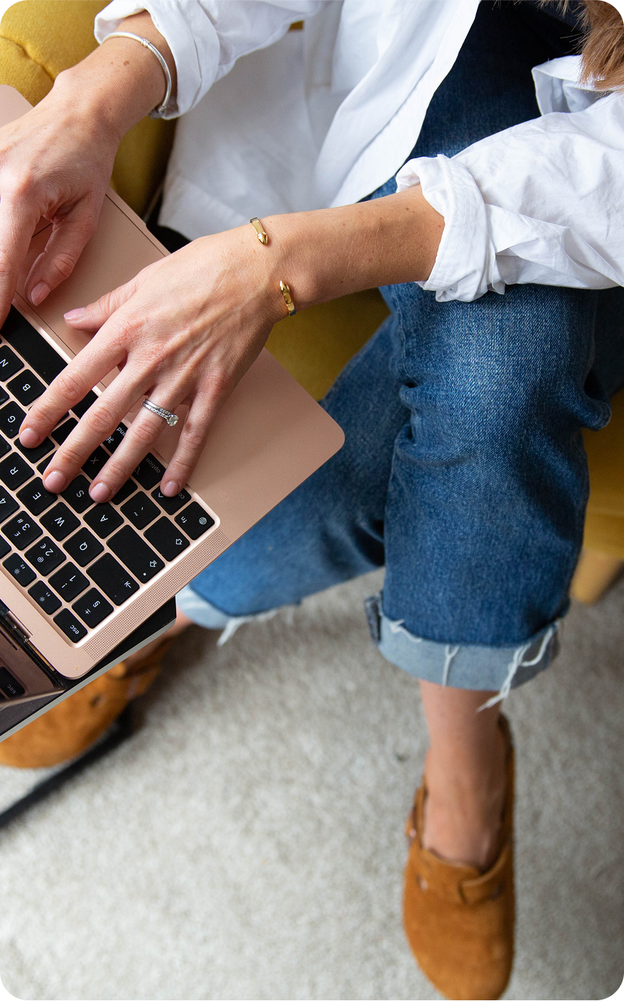 A woman is sitting on a couch using a laptop computer.