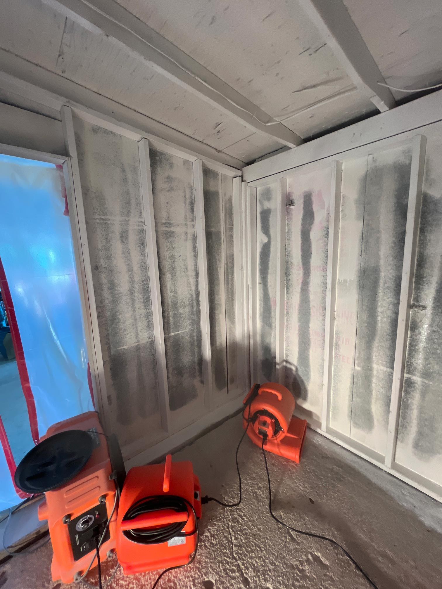 A room with a lot of white walls and two orange fans.