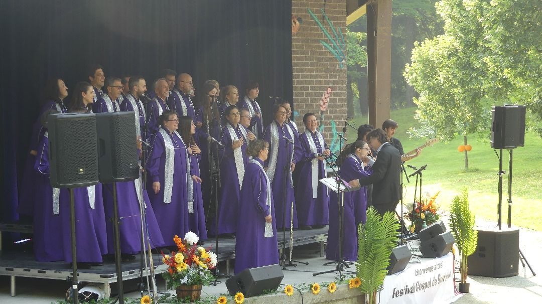Un groupe de personnes en robes violettes chantent sur une scène