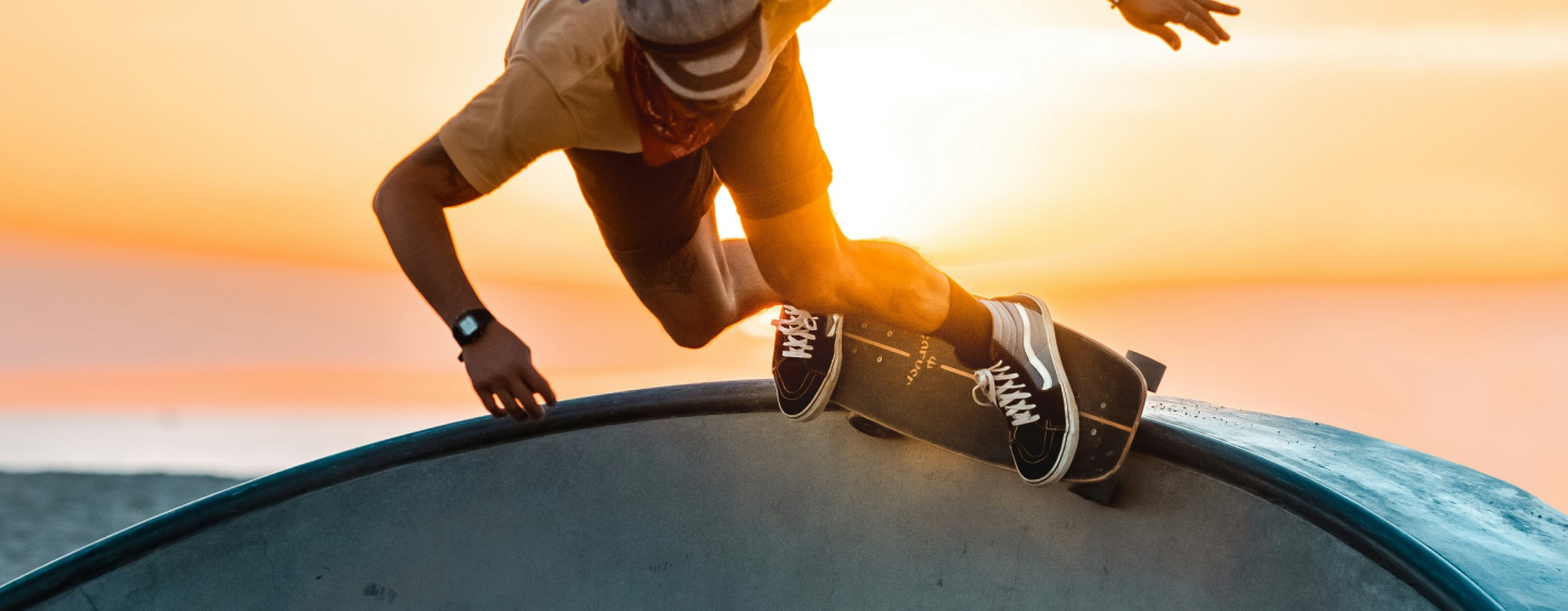 A man is riding a skateboard on a ramp at sunset.
