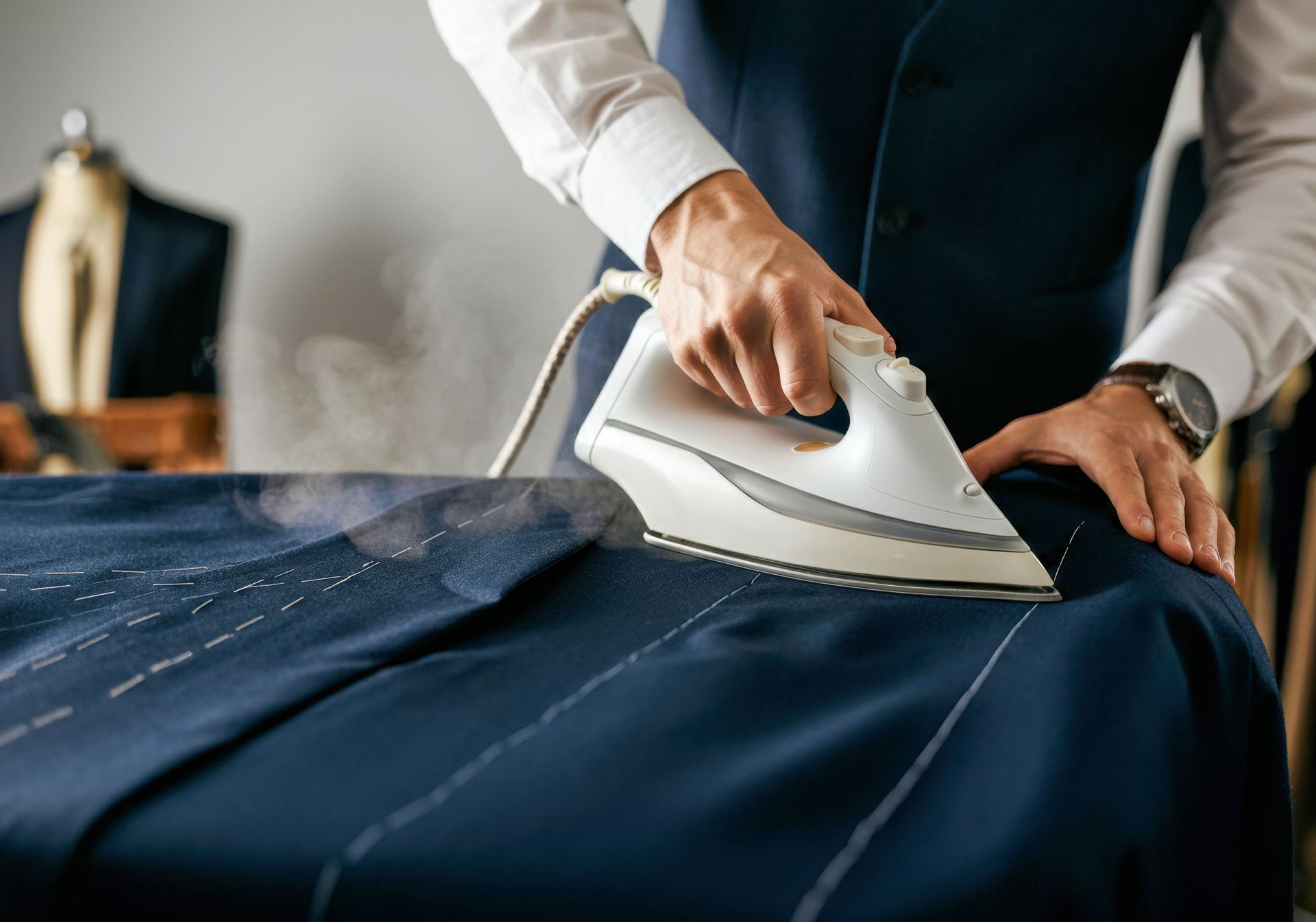 A man is ironing a suit on a table.