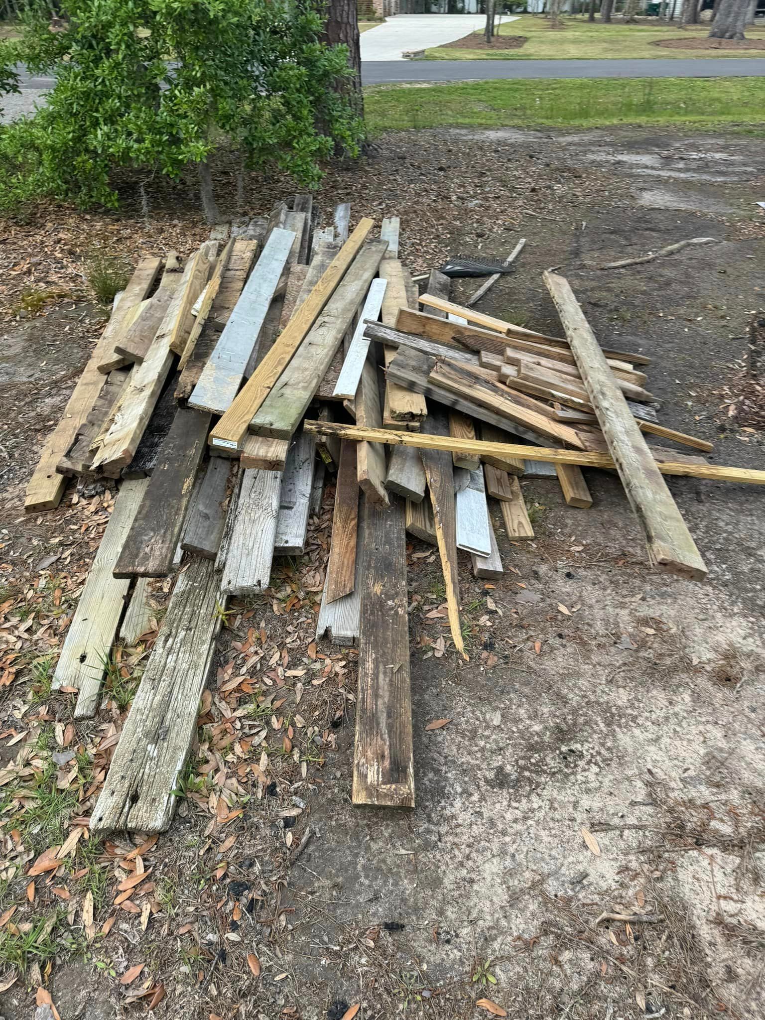 A pile of wood is sitting on the ground in a yard.