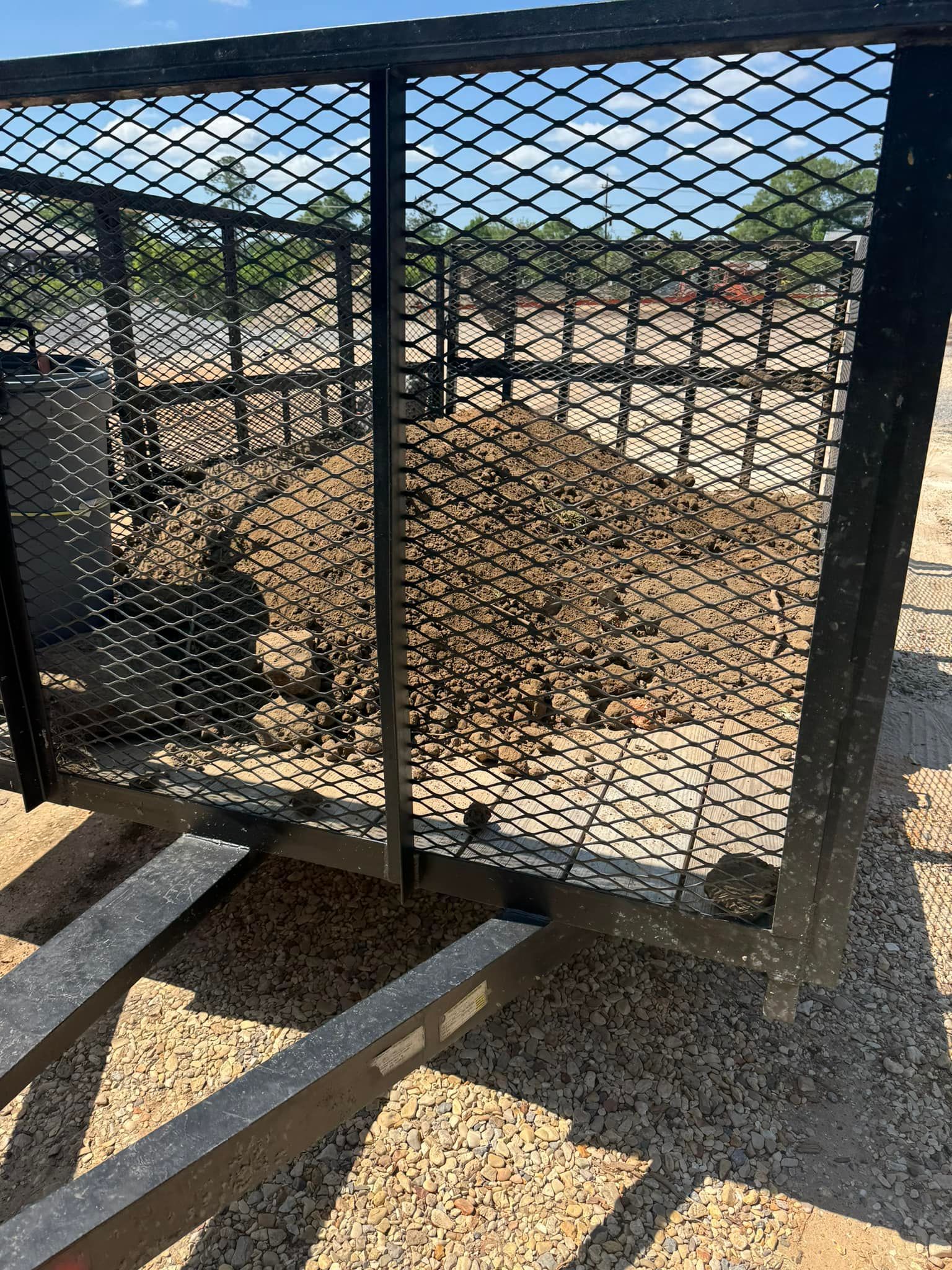 A metal fence is sitting on top of a dirt field.
