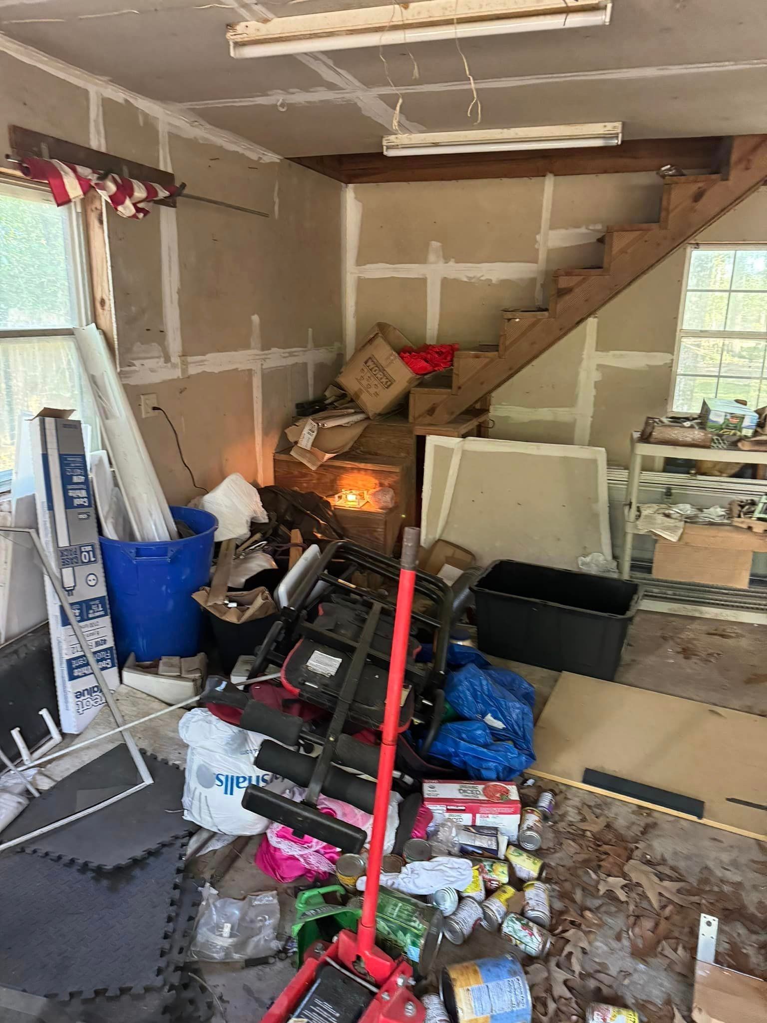 A garage filled with lots of junk and a staircase.