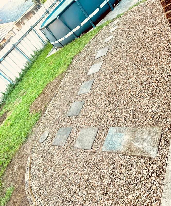 A gravel path leading to a pool in a backyard.