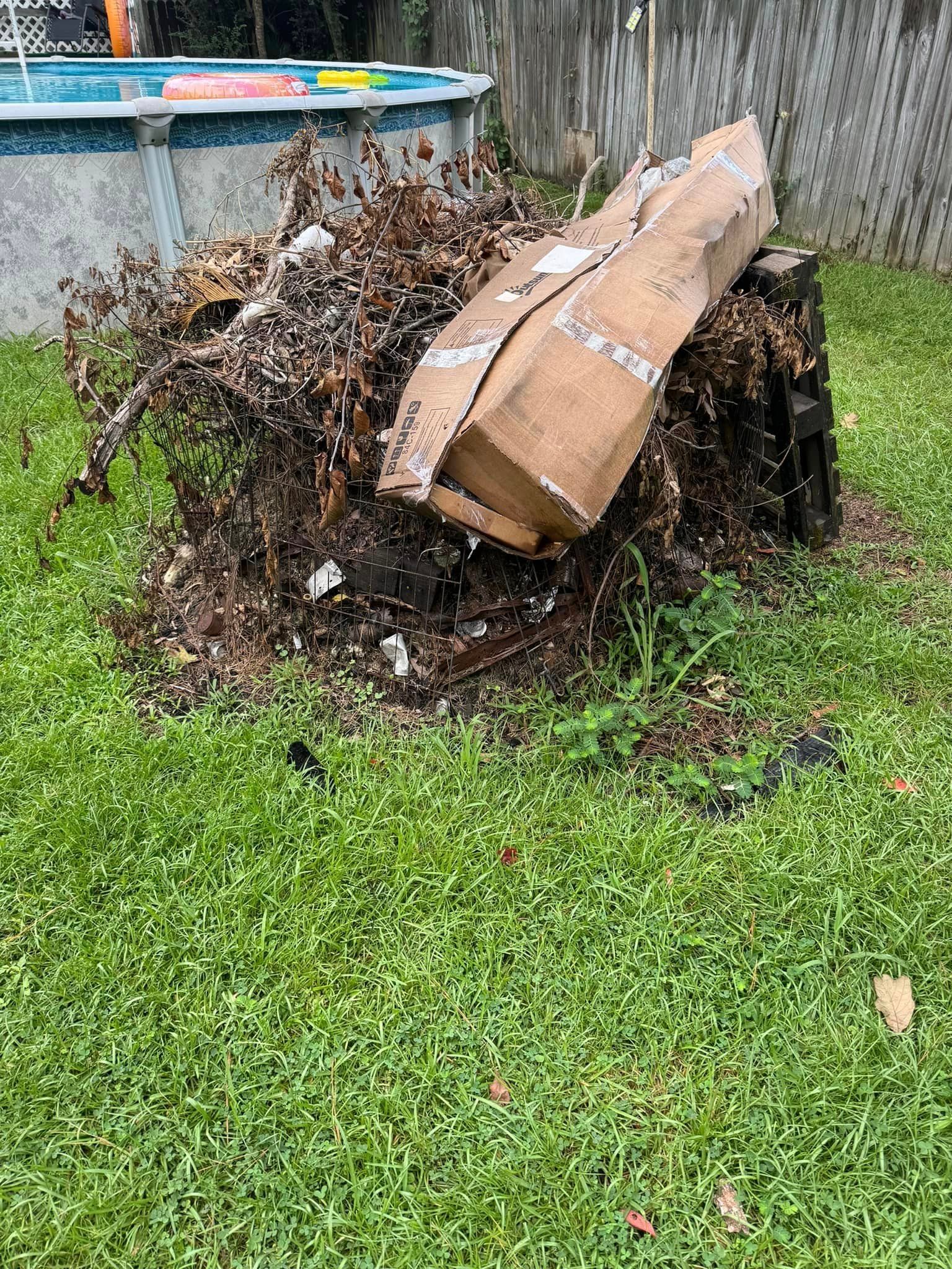 A pile of trash is sitting in the grass next to a pool.