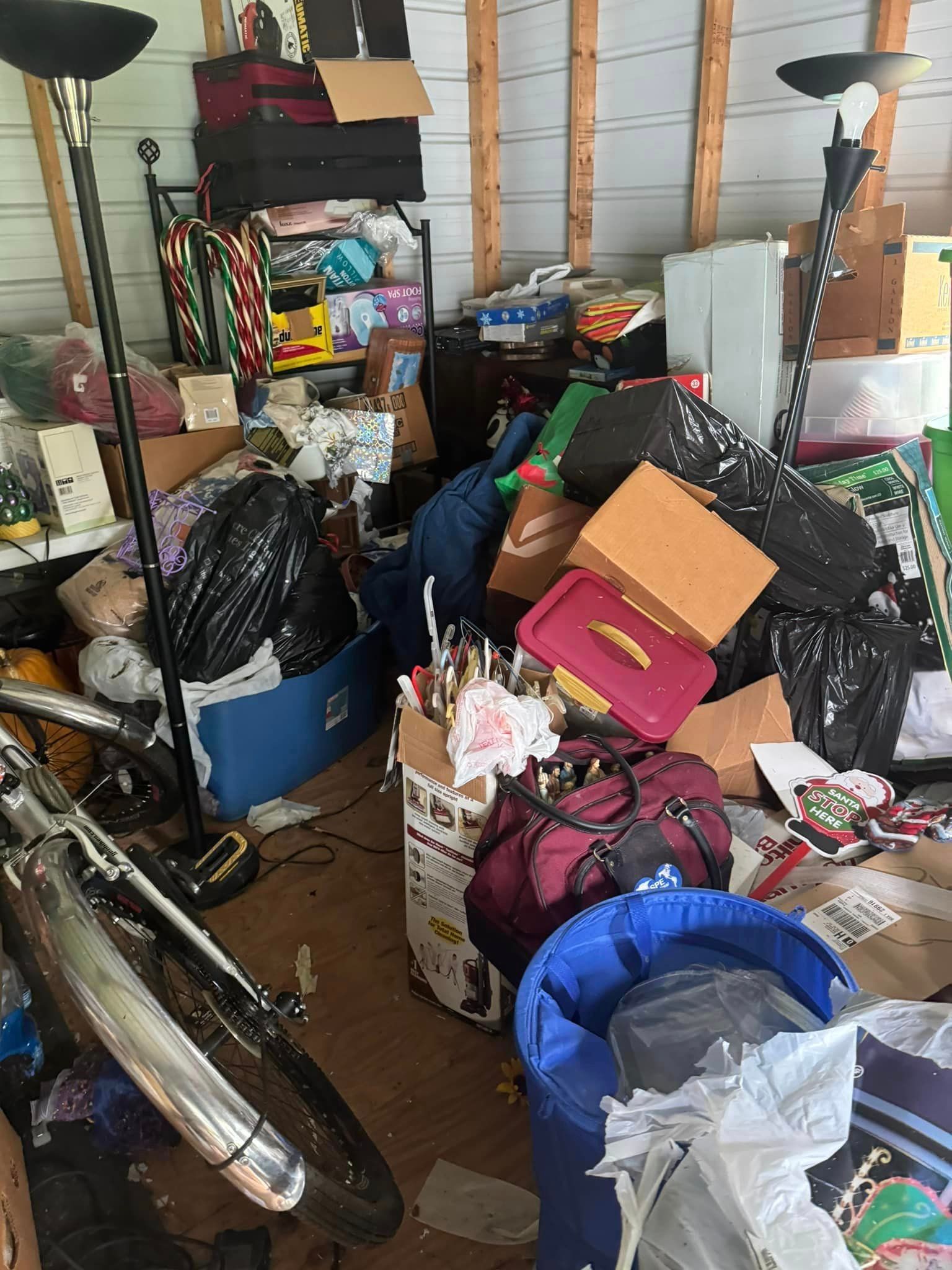 A garage filled with lots of boxes , bags , and a bicycle.