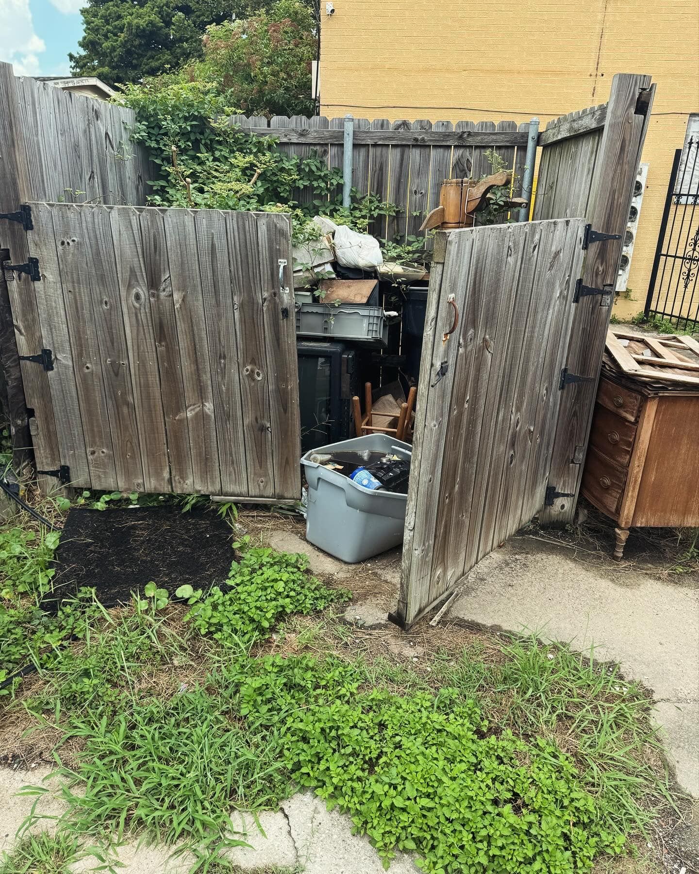 A wooden fence with a trash can inside of it.