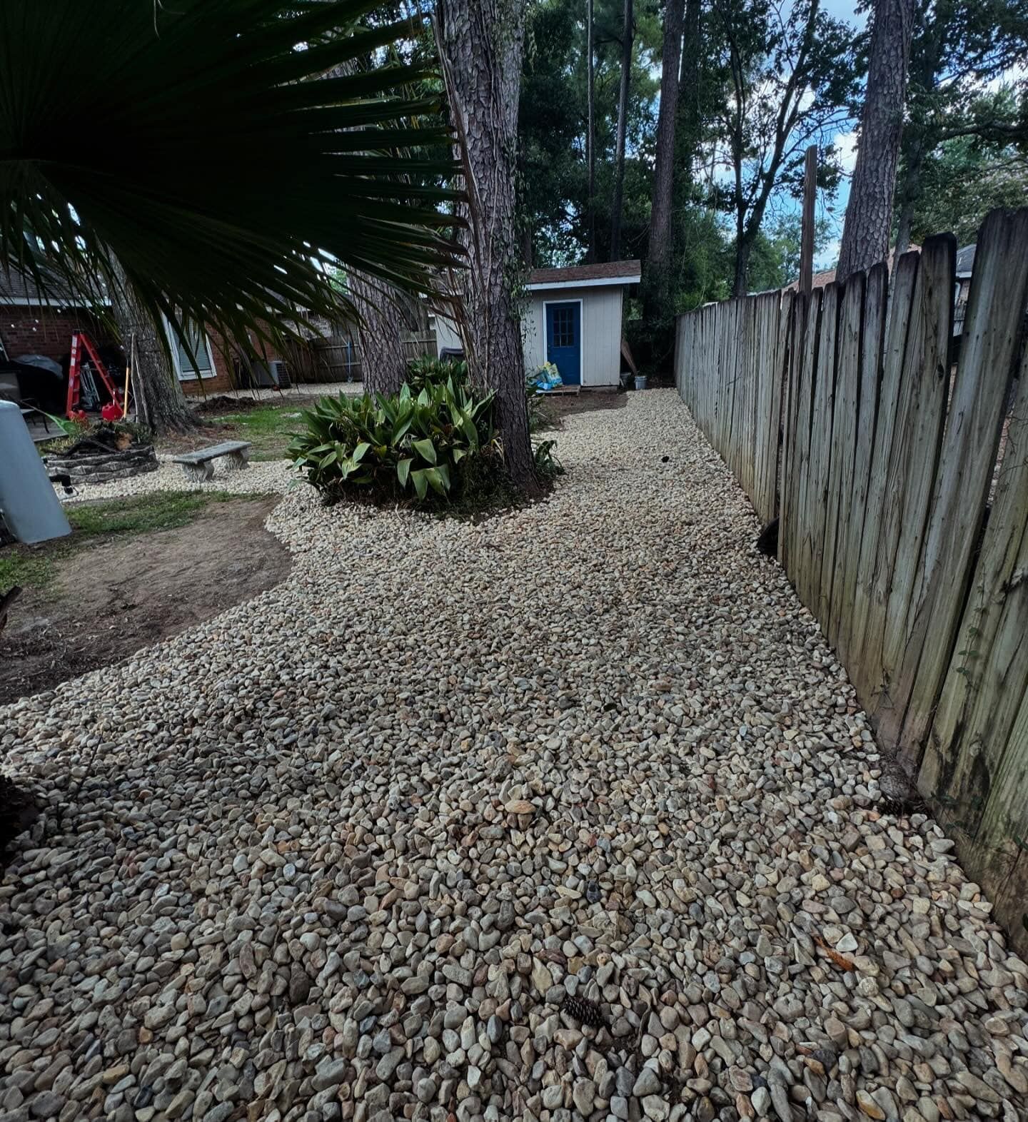 A gravel path leading to a house with a wooden fence.