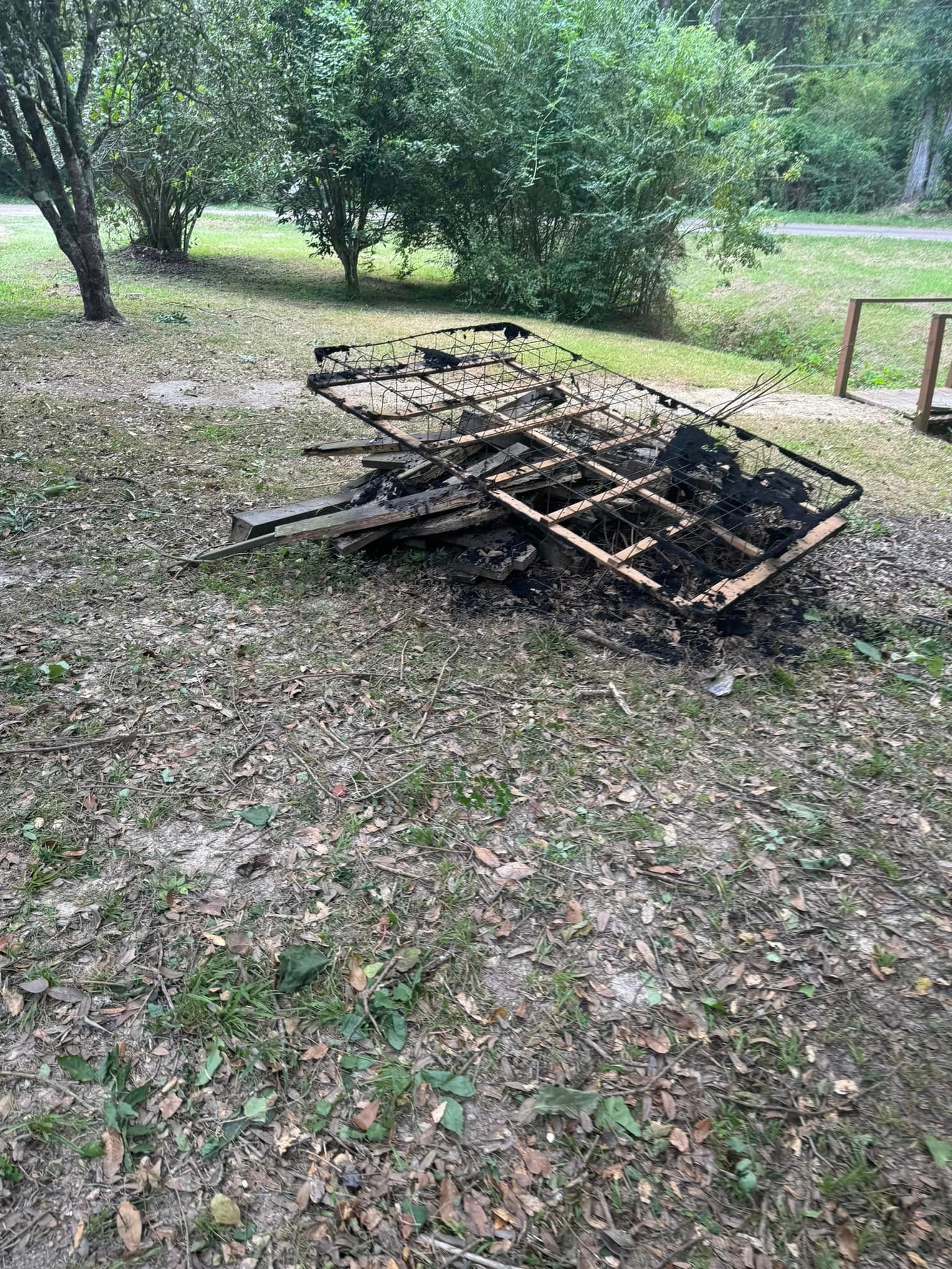 A pile of wood is sitting on the ground in a field.