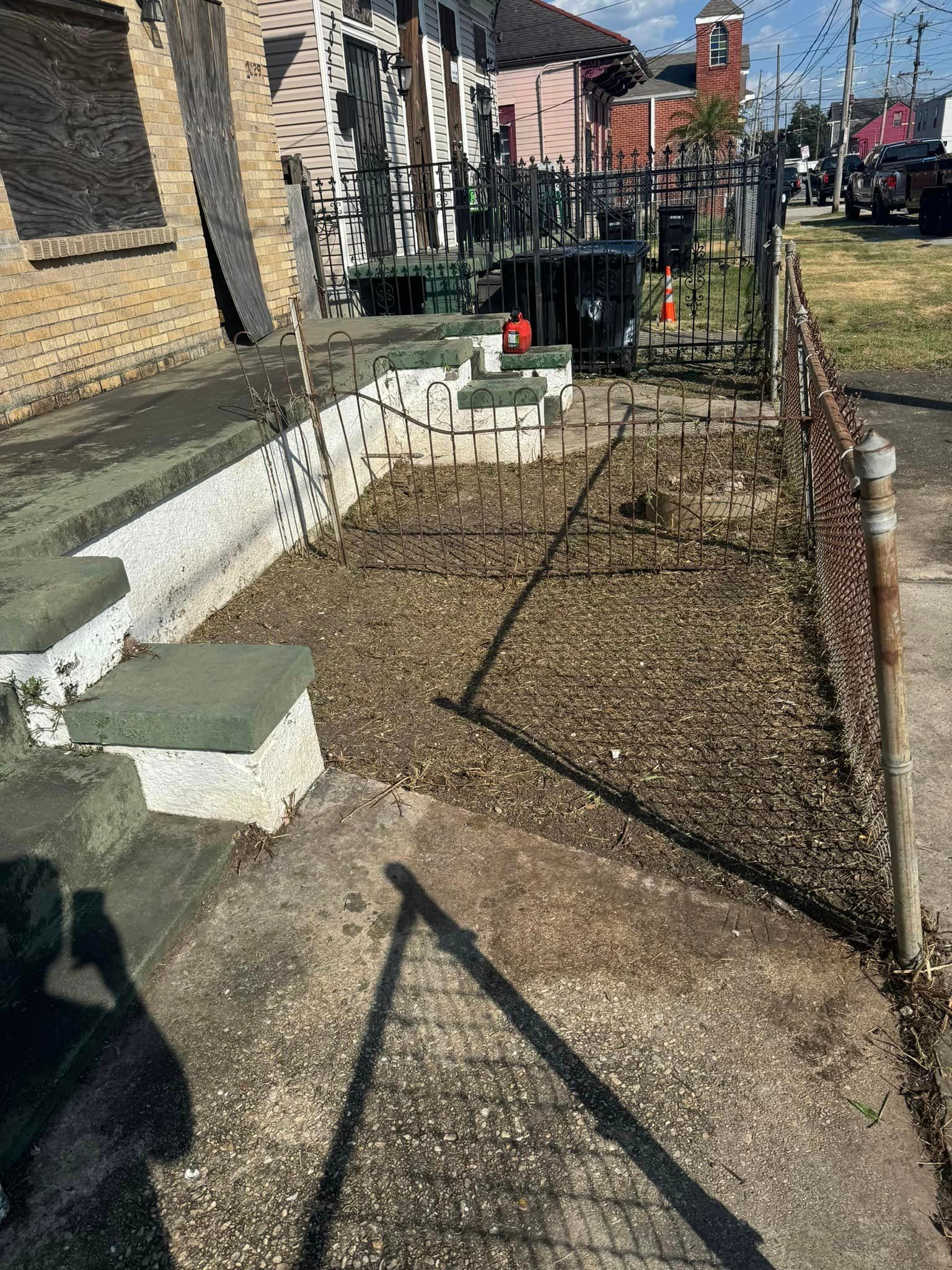 A concrete walkway leading to a house with stairs and a chain link fence.
