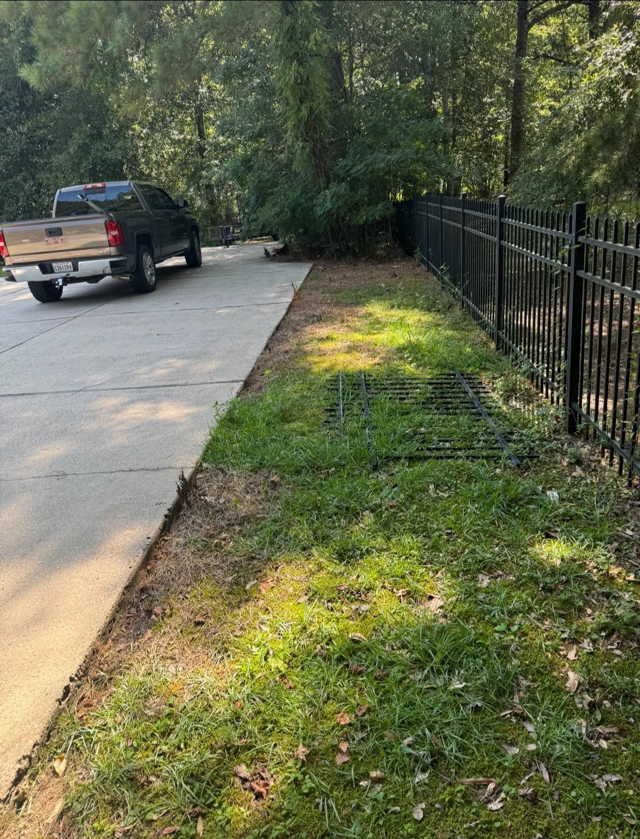 A truck is parked on the side of the road next to a fence.