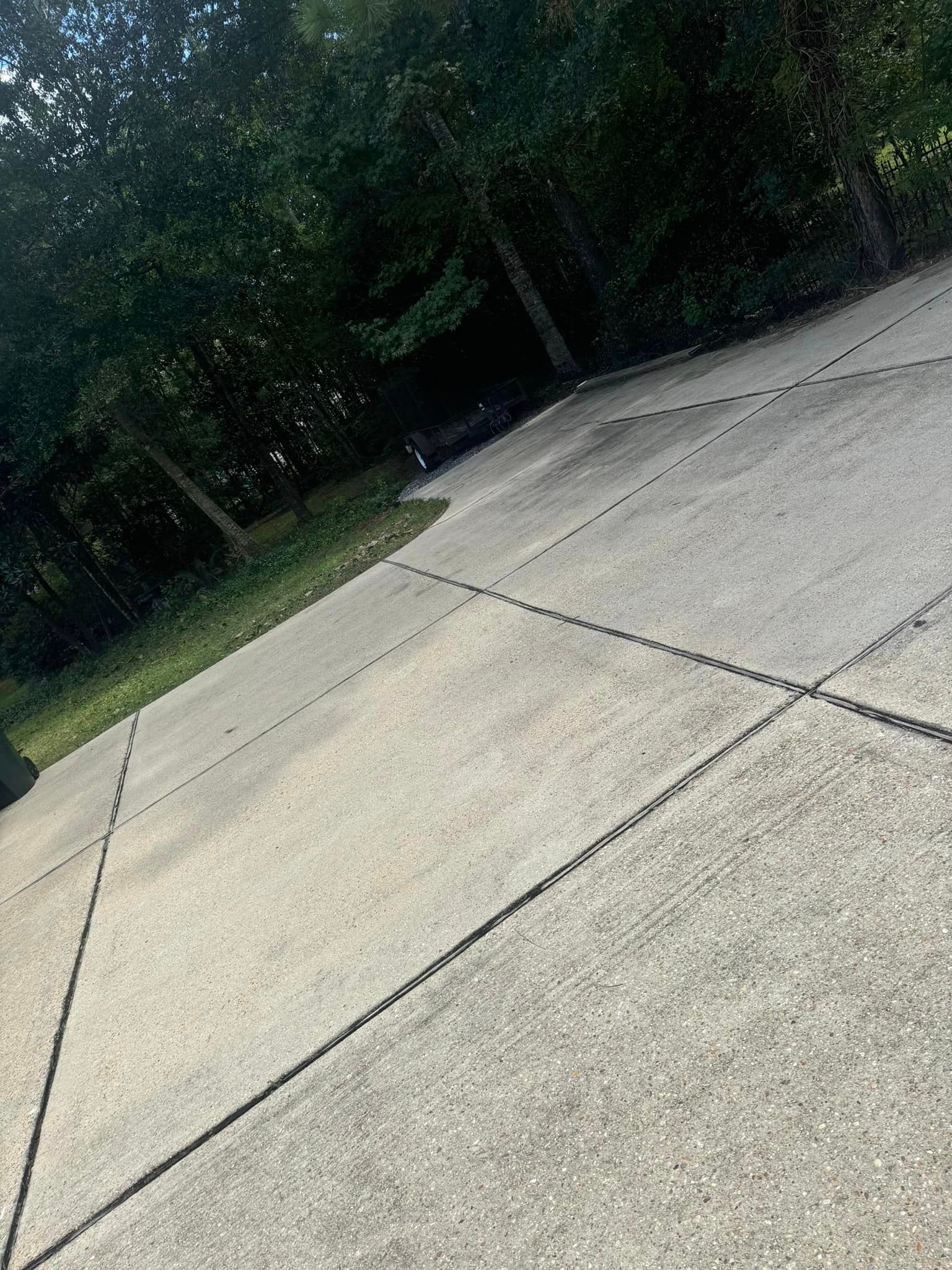 A concrete driveway with trees in the background.