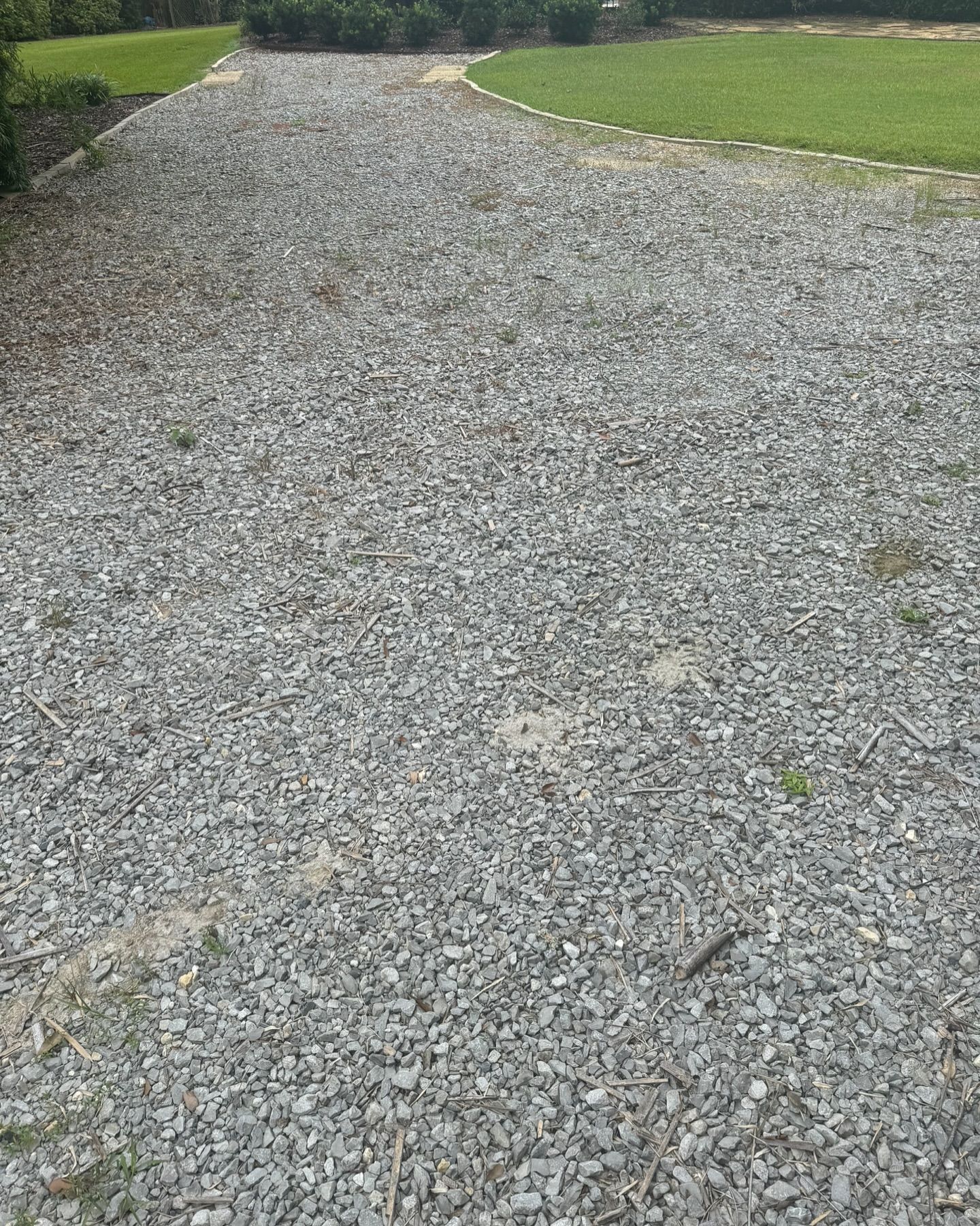 A gravel driveway leading to a grassy field.