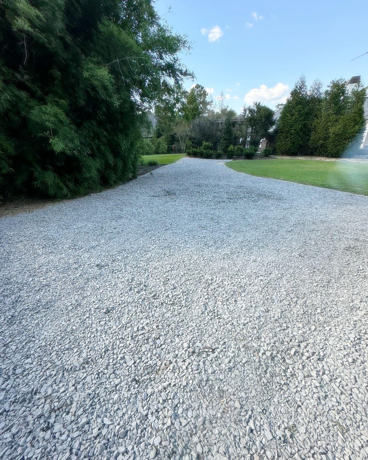 A gravel driveway going through a lush green field