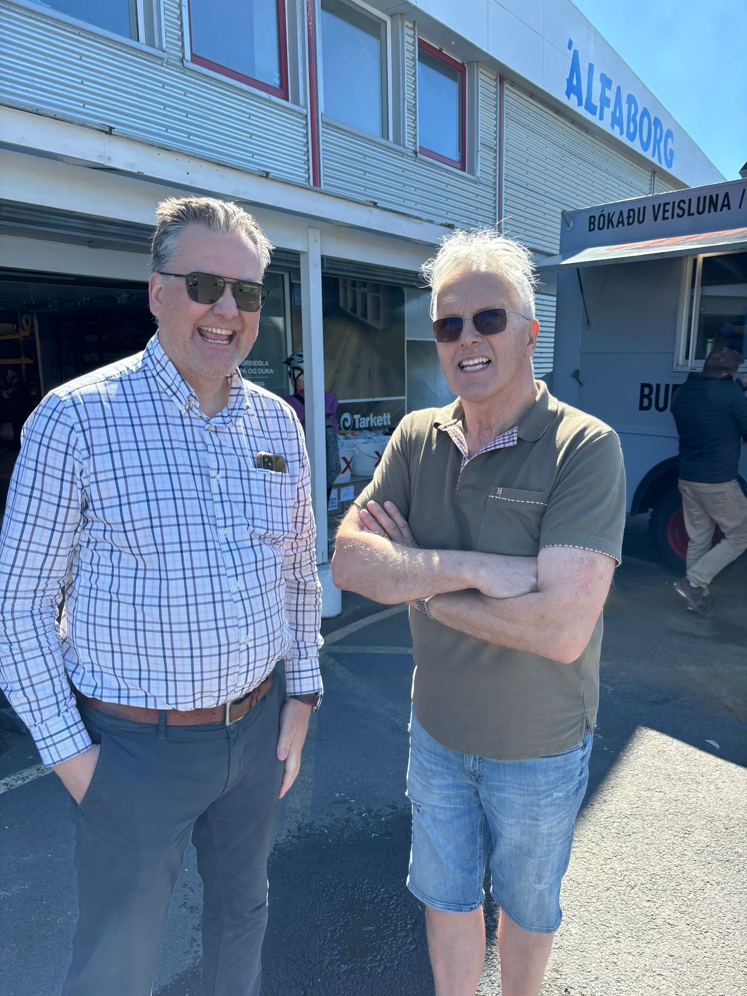 Tveir menn standa við hlið hvors annars fyrir framan byggingu.