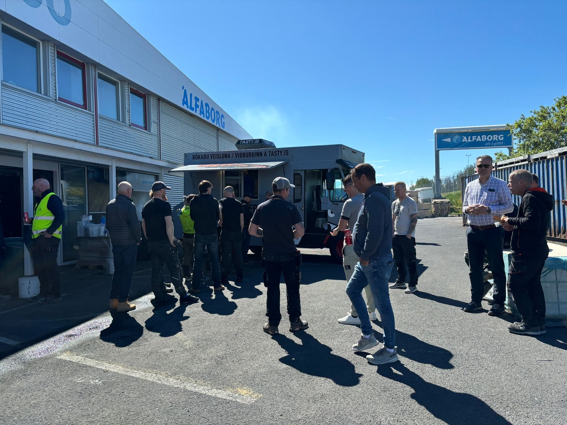 Hópur manna stendur fyrir framan byggingu.