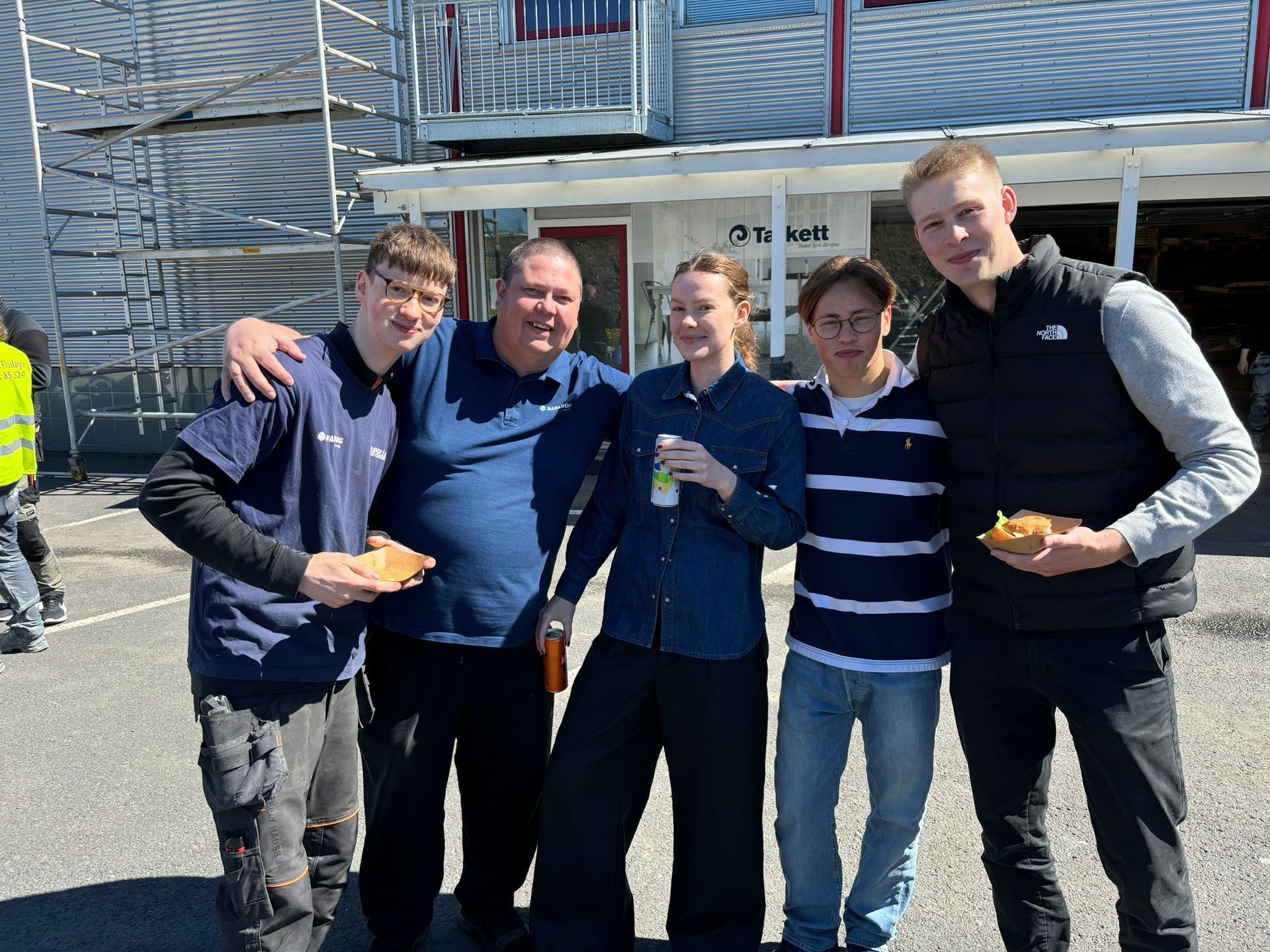 Hópur fólks situr fyrir á mynd fyrir framan byggingu.