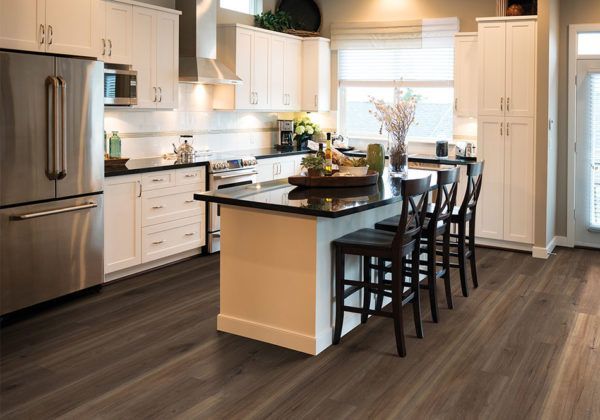 Eldhús með hvítri innréttingu og tækjum úr ryðfríu stáli og stór eyja.