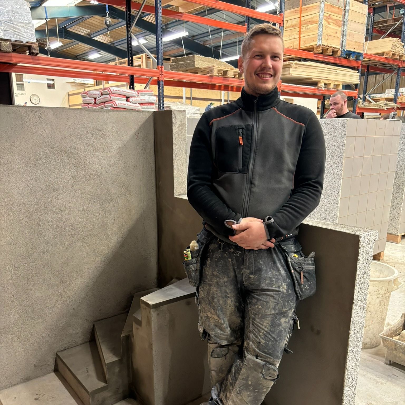 Maður hallar sér upp að vegg í vöruhúsi.